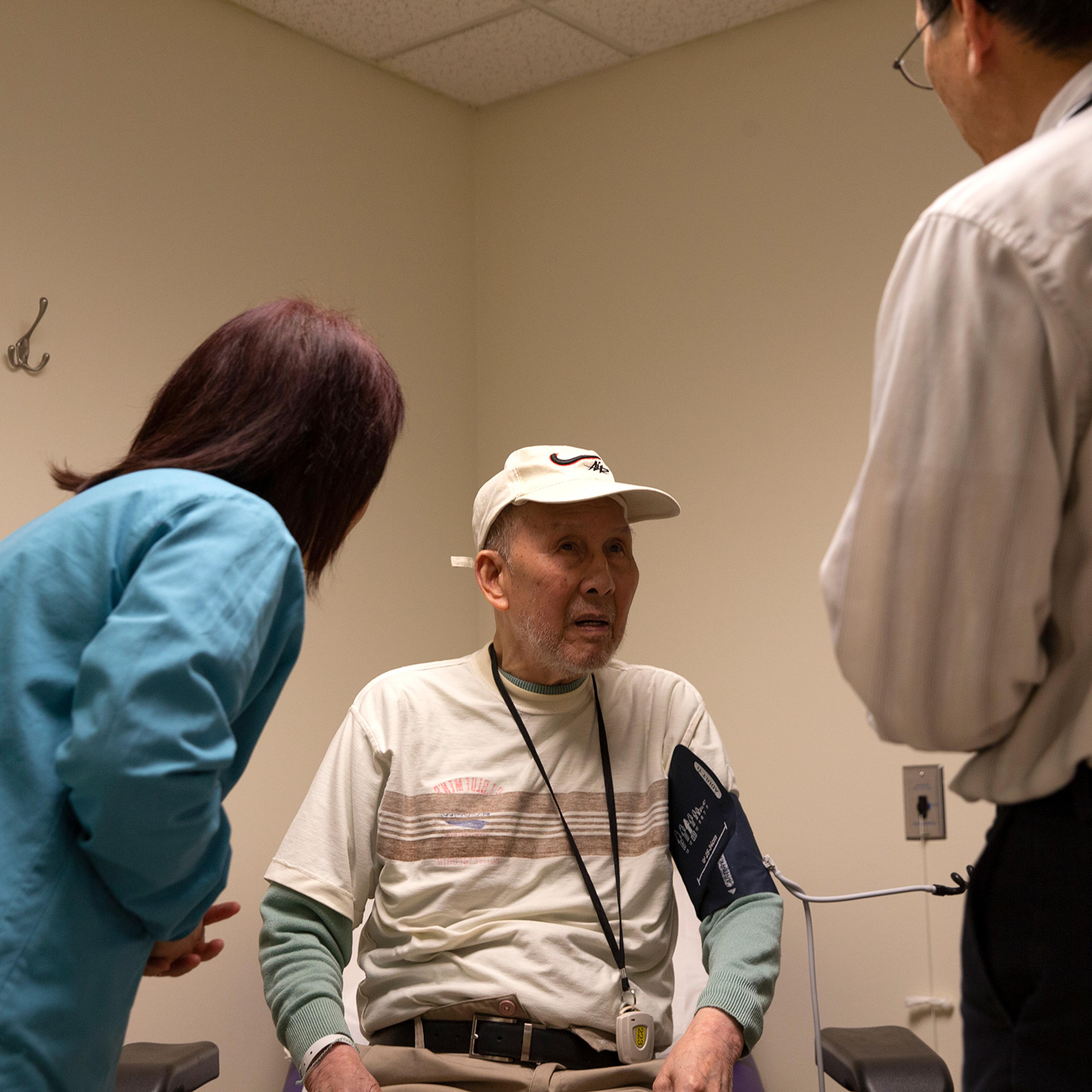 Bing Hong Liu (C) talks to to Dr. Alan Chun (R) through an interpreter at the International Community Health Services medical clinic in their assisted living facility, the Legacy House, on March 20 in Seattle.