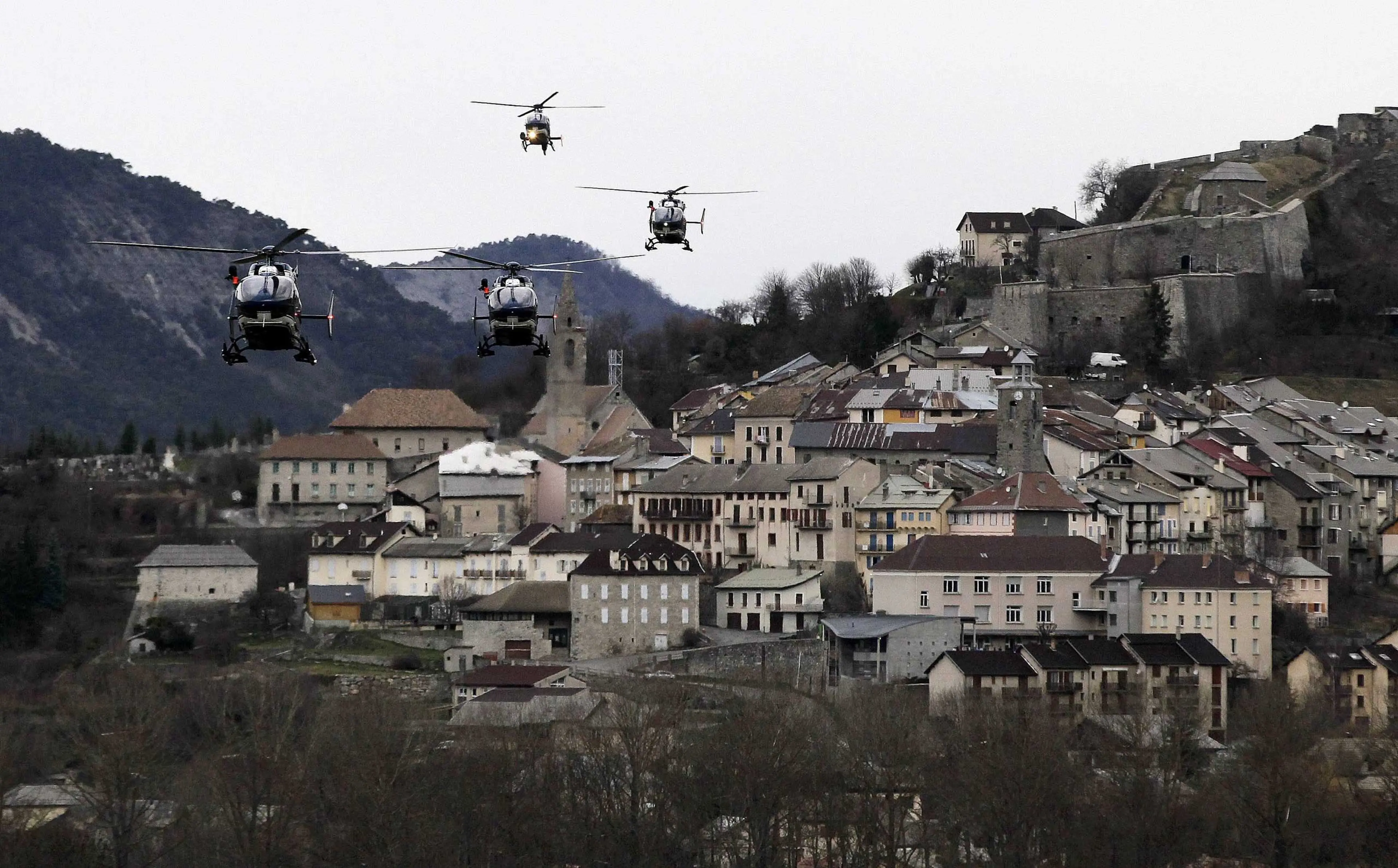 Helicopters of the French gendarmerie and emergency services fly over Seyne-les-Alpes as they resume works to recover the bodies and the remains of the Airbus A320 that crashed the previous day in the Alps, March 25, 2015.