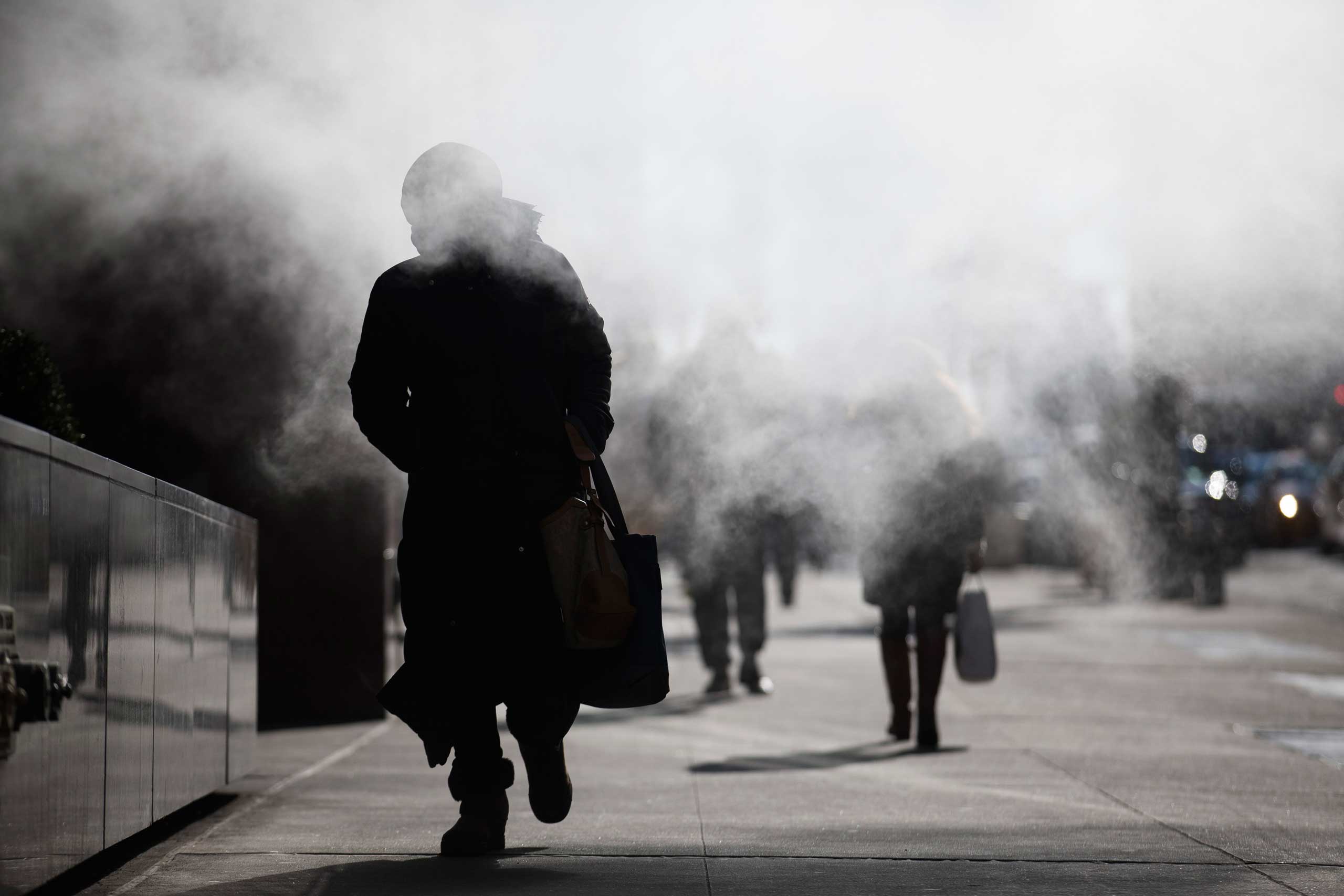 A pedestrian walks through the exhaust of a steam vent during a frigid morning commute, Friday, Feb. 20, 2015, in New York.