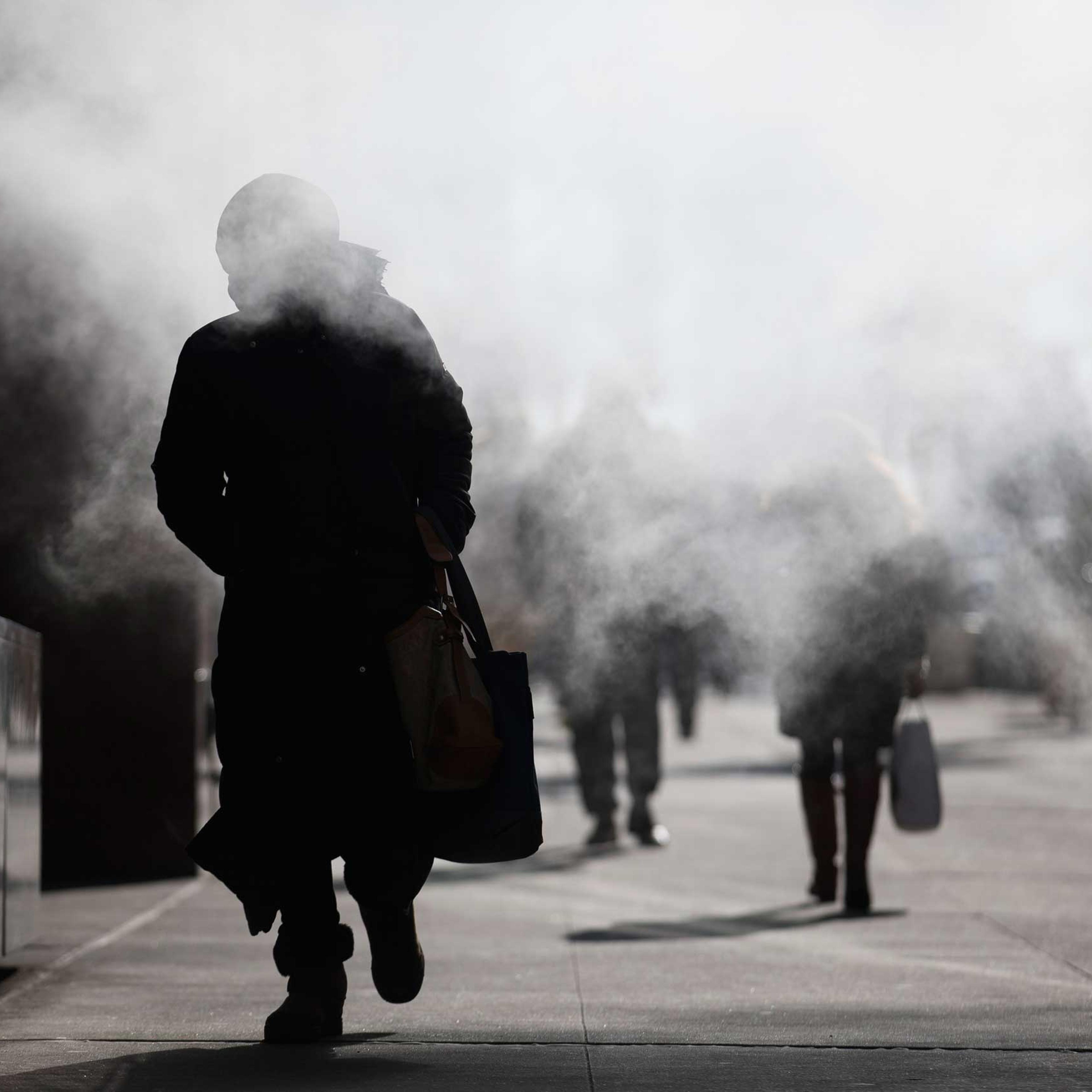 A pedestrian walks through the exhaust of a steam vent during a frigid morning commute, Friday, Feb. 20, 2015, in New York.
