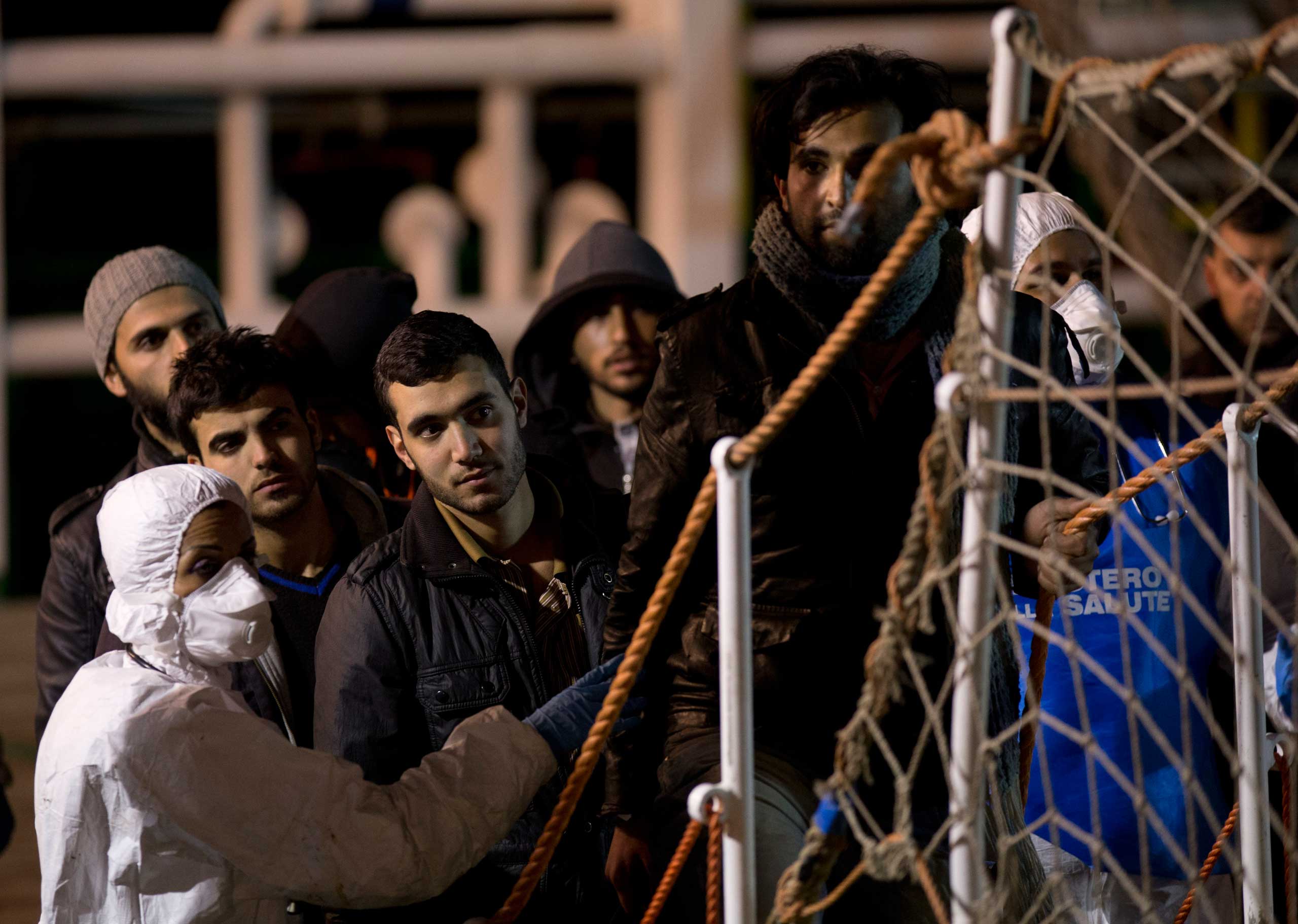Migrants wait to disembark, after being rescued by a merchant vessel, in the Sicilian harbor of Pozzallo, Italy, early on April 20, 2015.