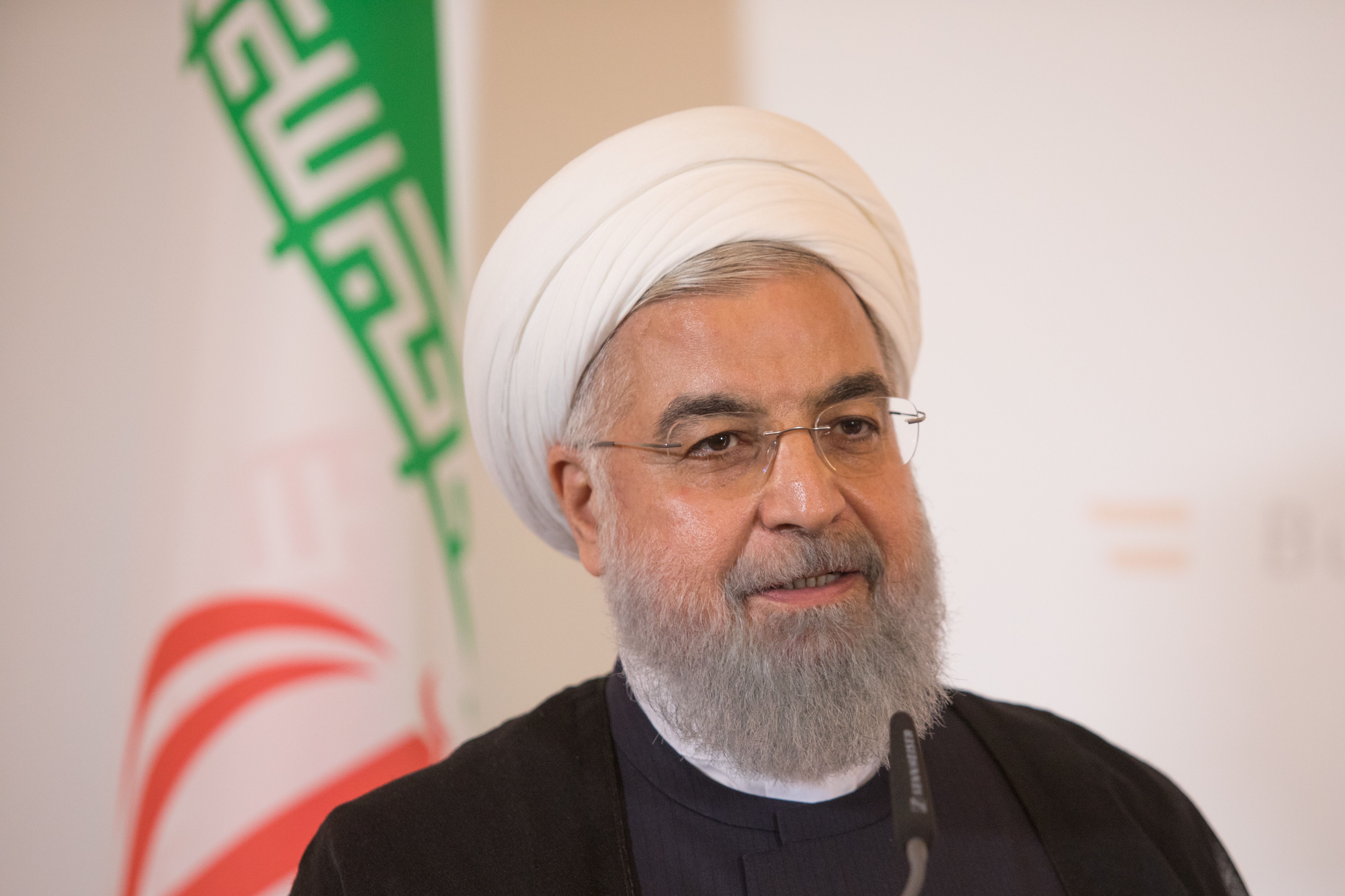 Iranian President Rouhani speaks onstage with the Iranian flag behind him
