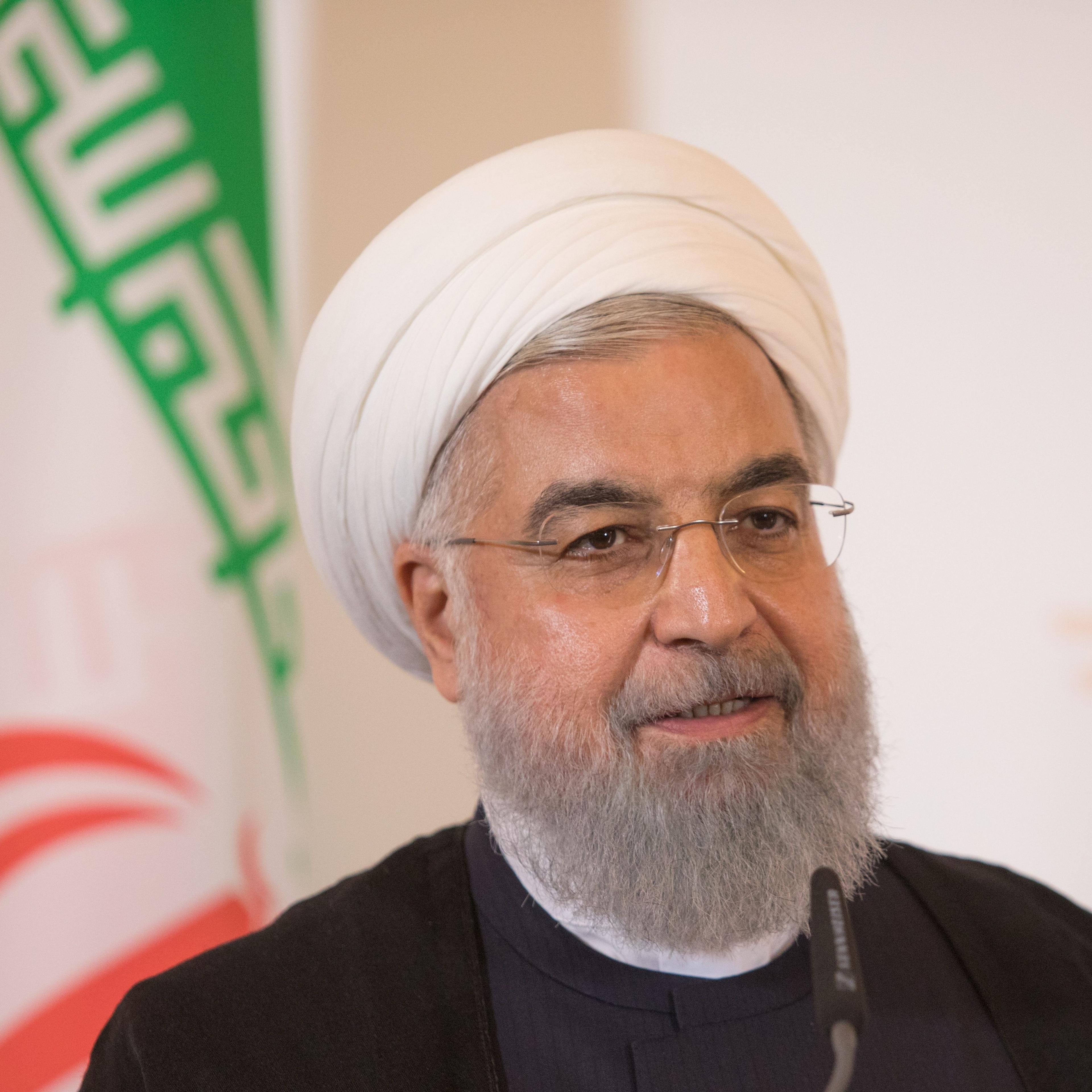 Iranian President Rouhani speaks onstage with the Iranian flag behind him