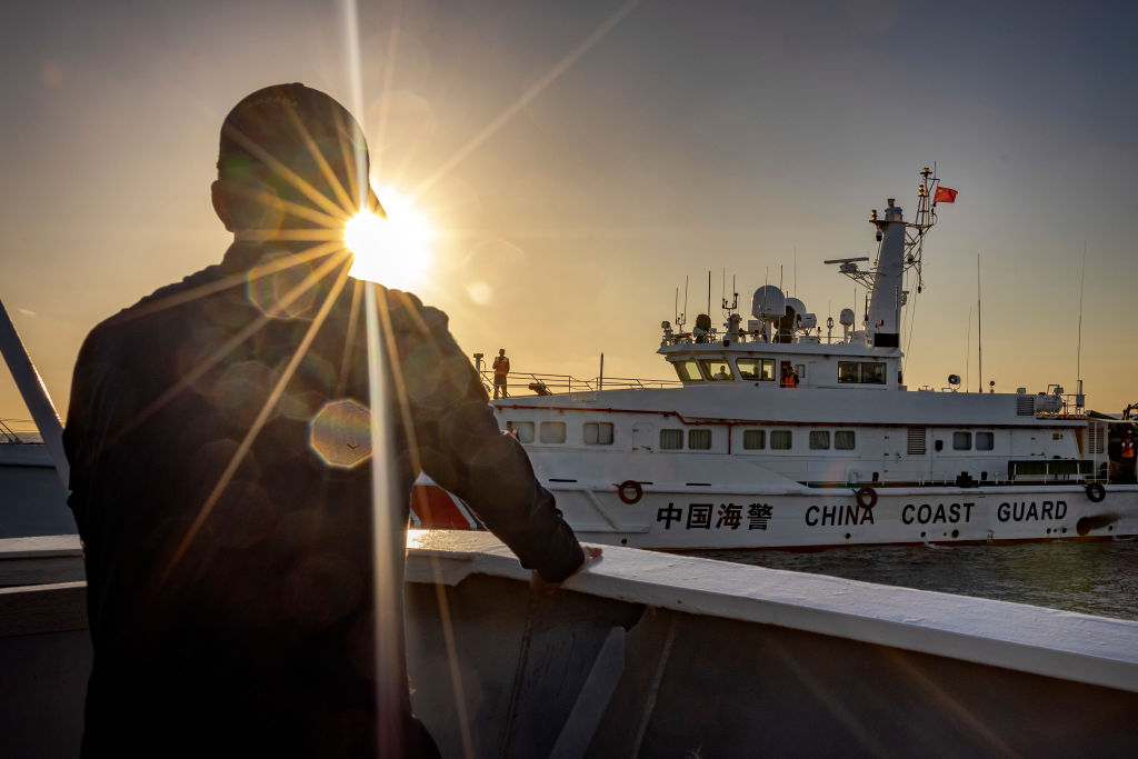 A Philippine Coast Guard personnel aboard BRP Sindangan looks on as a Chinese Coast Guard ship sails nearby, during resupply mission to troops stationed at Second Thomas Shoal, on March 5, 2024 in the South China Sea.