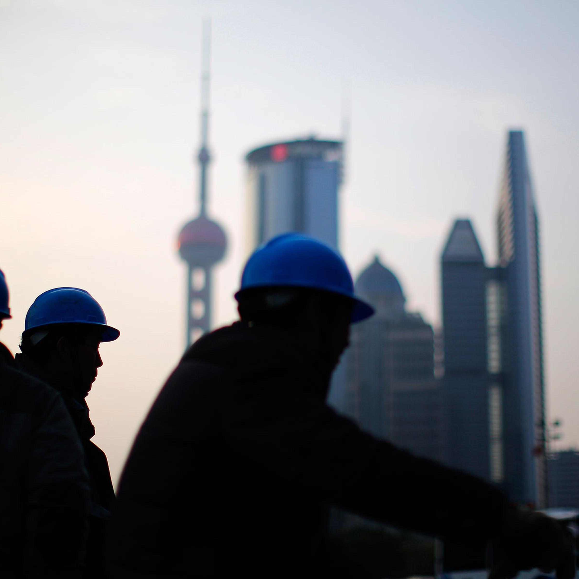Construction workers stand on a street corner at the financial district of Pudong in Shanghai on March 11, 2014