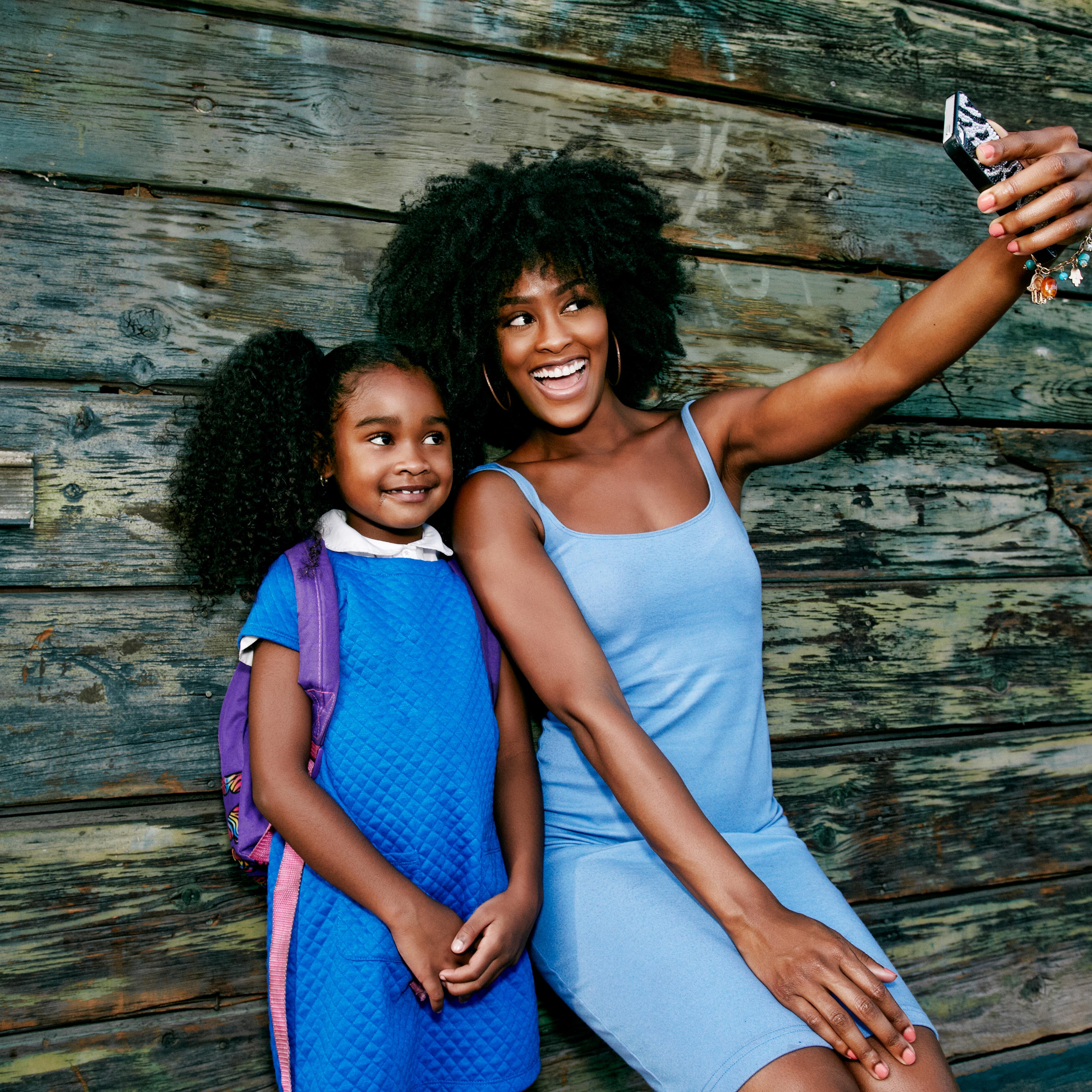 Black mother and daughter posing for cell phone selfie