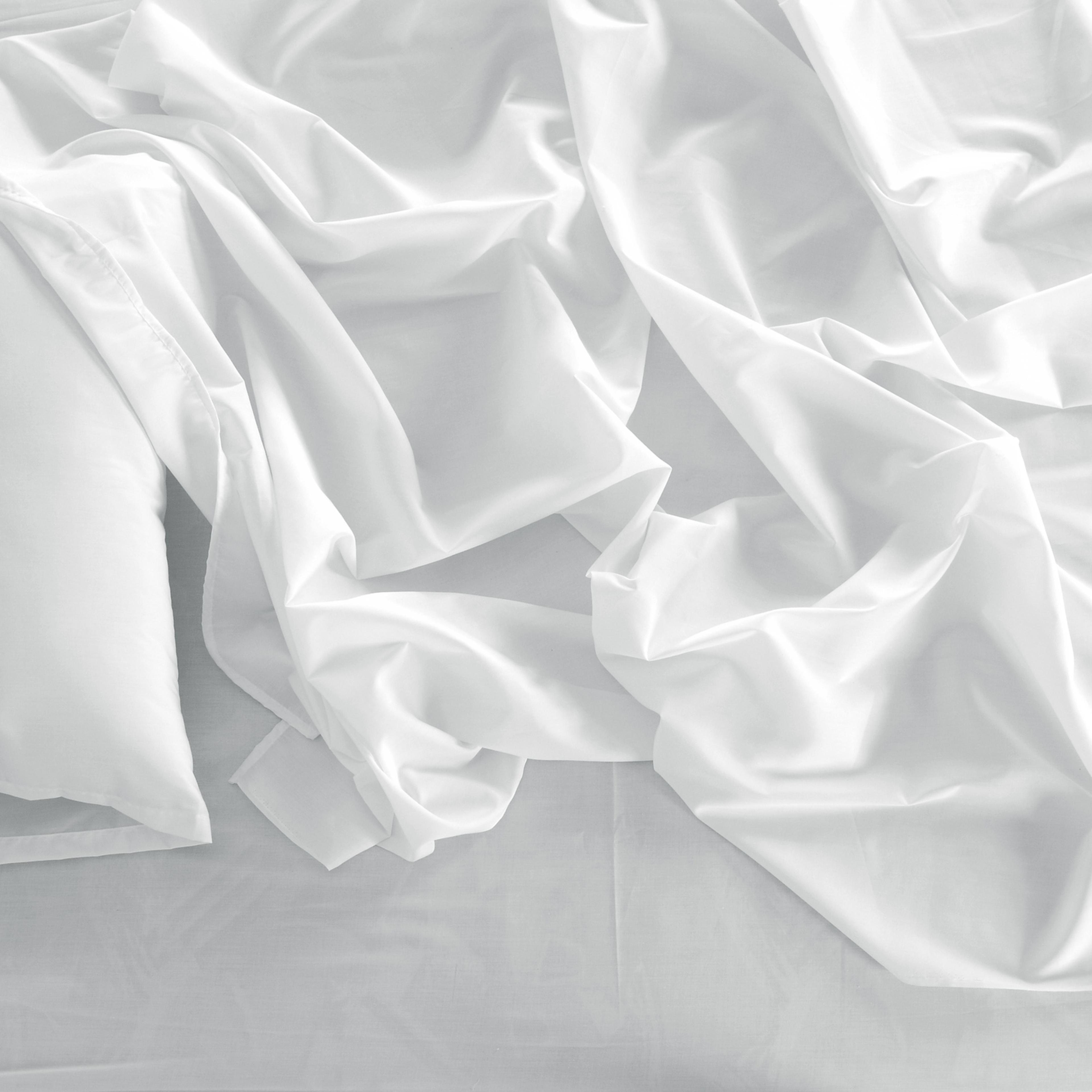 A white linen messed up bed sheets and a white pillow