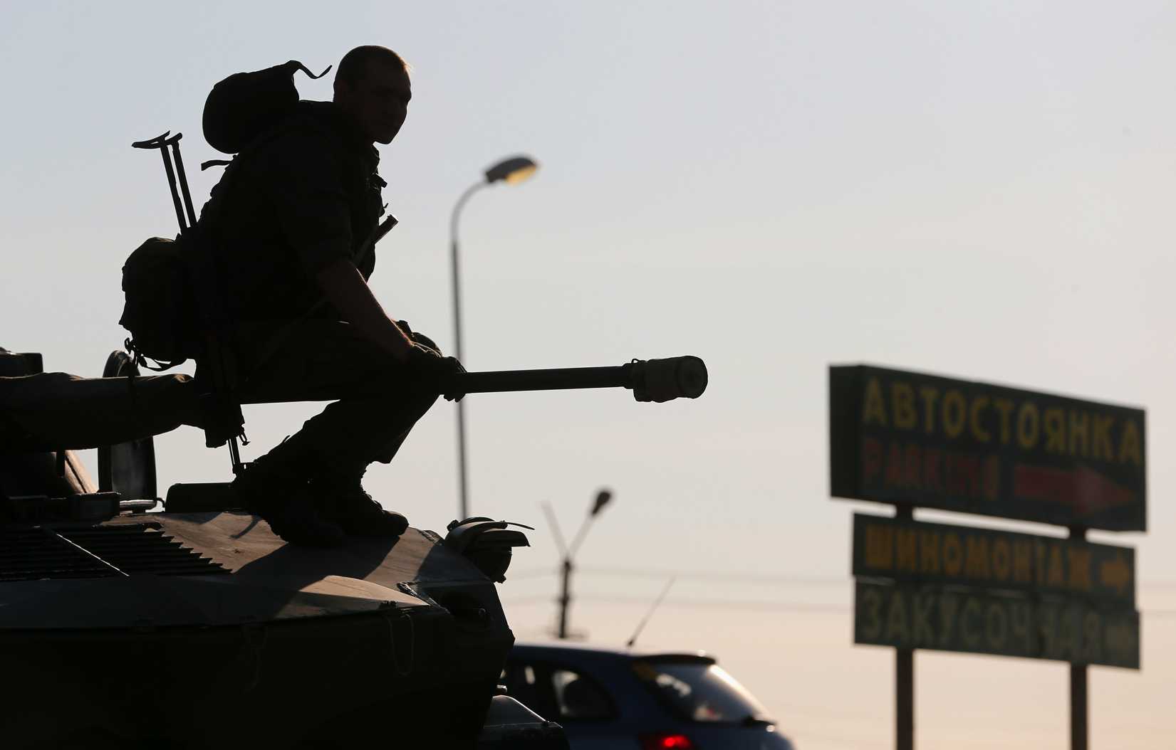 A Russian serviceman sits atop an armored vehicle outside Kamensk-Shakhtinsky, Russia's Rostov region, on Aug. 15, 2014. Dozens of heavy Russian military vehicles amassed on Friday near the border with Ukraine where a huge Russian convoy with humanitarian aid came to a halt as Moscow and Kiev struggled to agree border crossing procedures