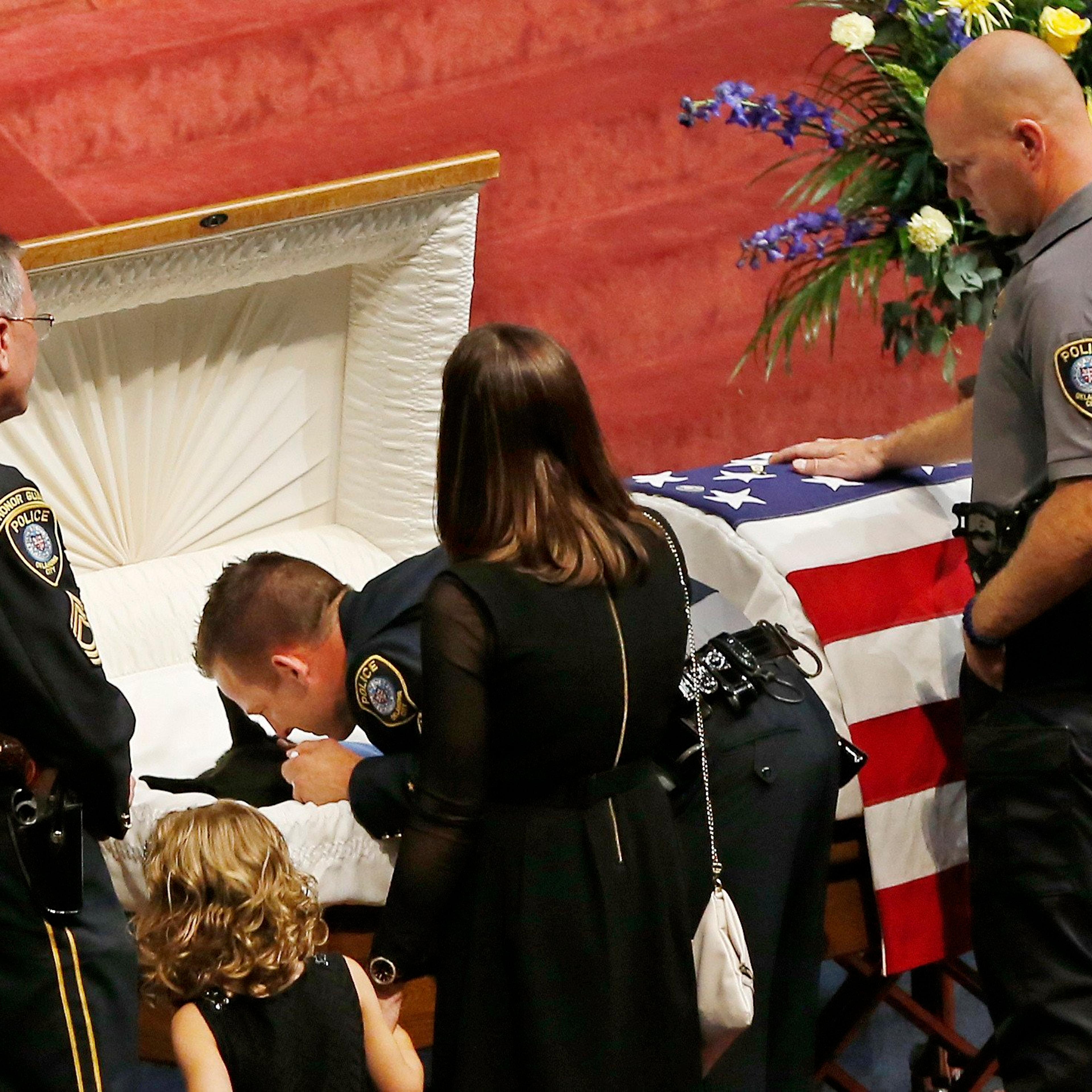 Oklahoma City police officer Sgt. Ryan Stark, center, leans over the casket of his canine partner, K-9 Kye, following funeral services for the dog in Oklahoma City, on Aug. 28, 2014.