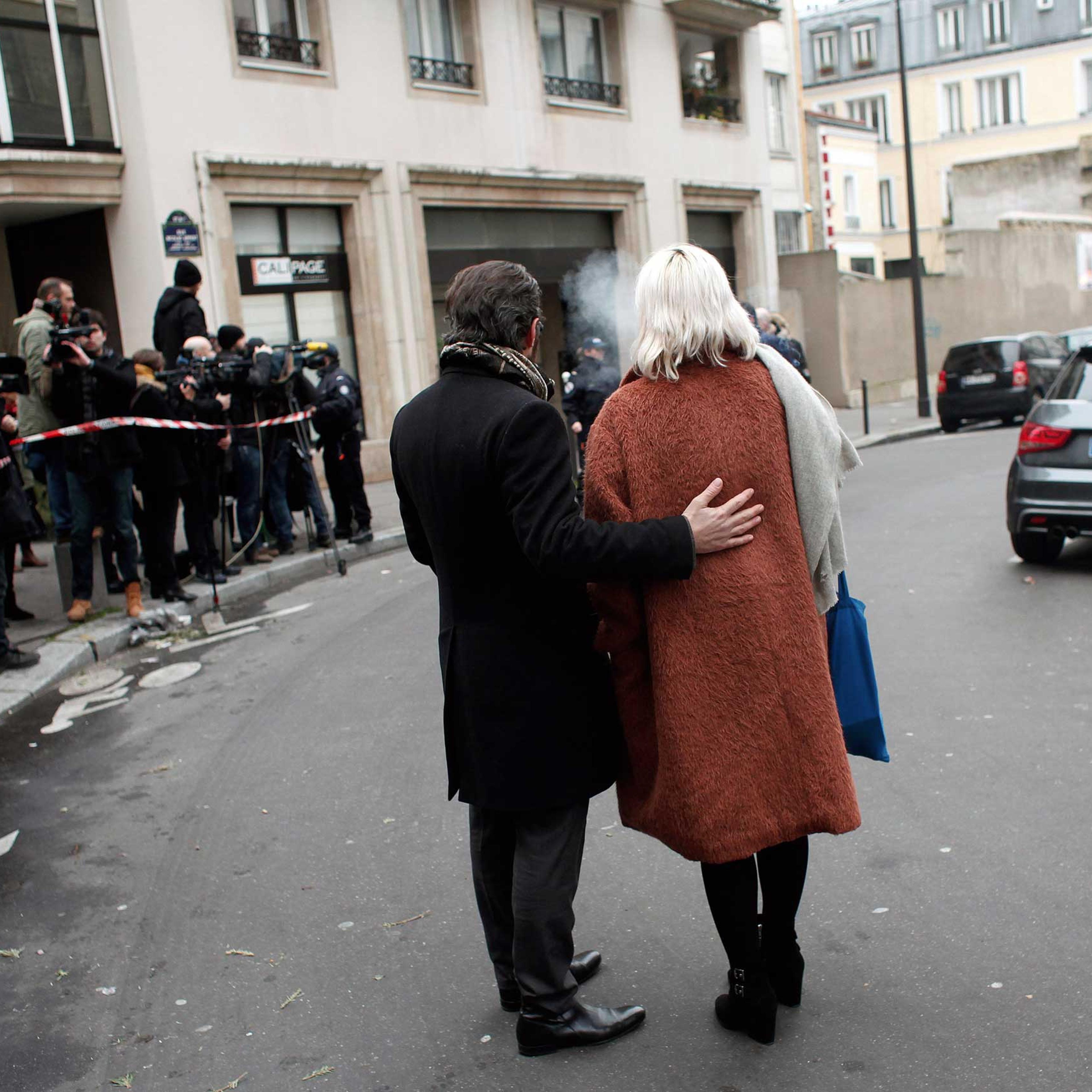 People stand outside the French satirical newspaper Charlie Hebdo's office after a shooting, in Paris, Jan. 7, 2015.
