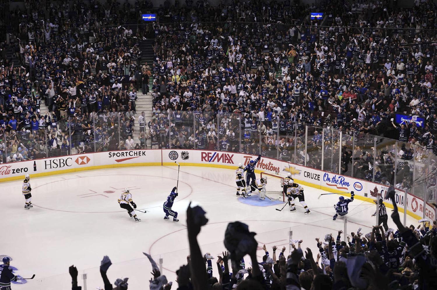 Fans and Canucks players erupt in cheers after Alexandre Burrows (14) scores the game-winning goal 11 seconds into overtime in game two of the Stanley Cup Finals.