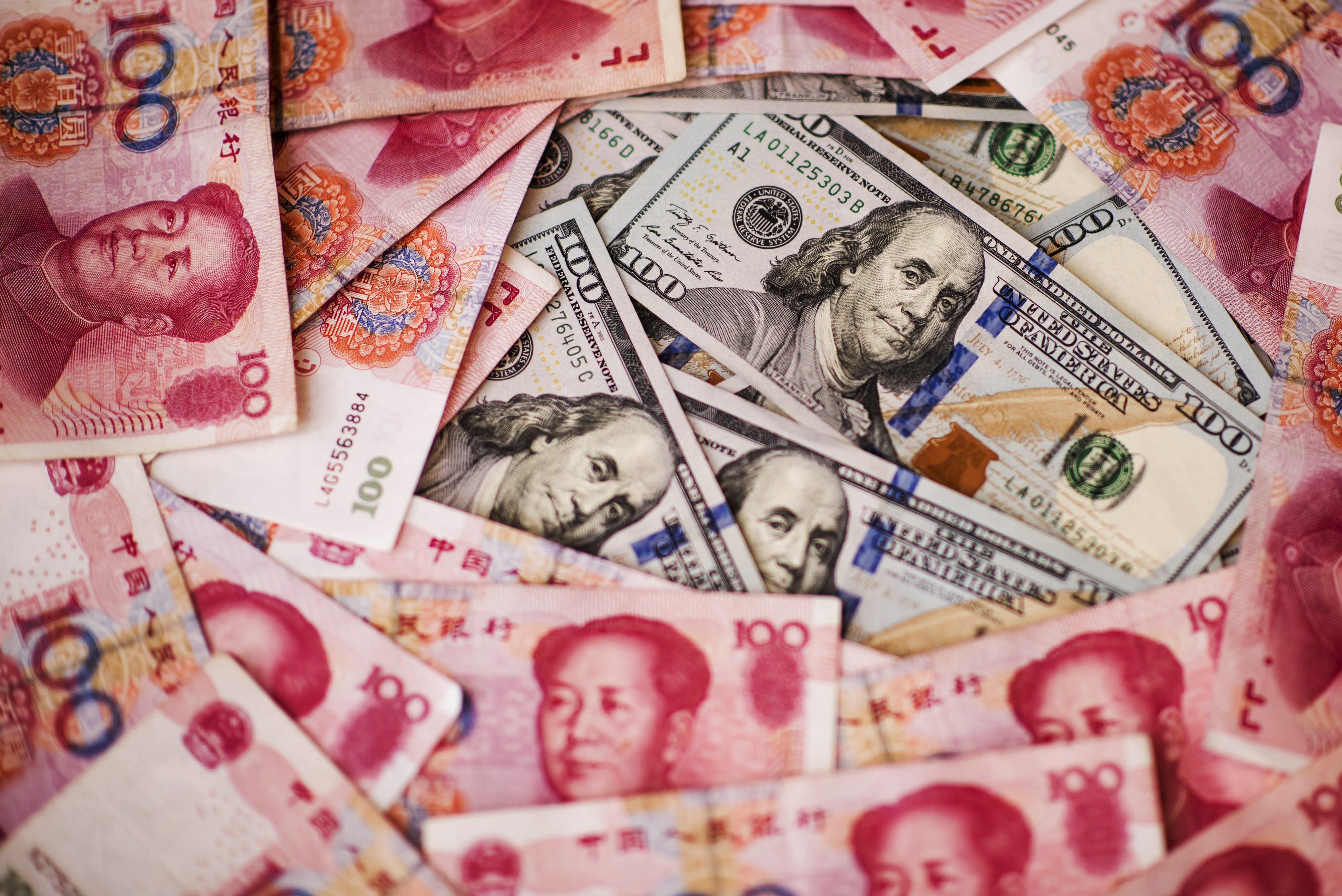 U.S. one-hundred dollar bills and Chinese one-hundred yuan banknotes are arranged for a photograph in Hong Kong, China, on Monday, July 20, 2015. 