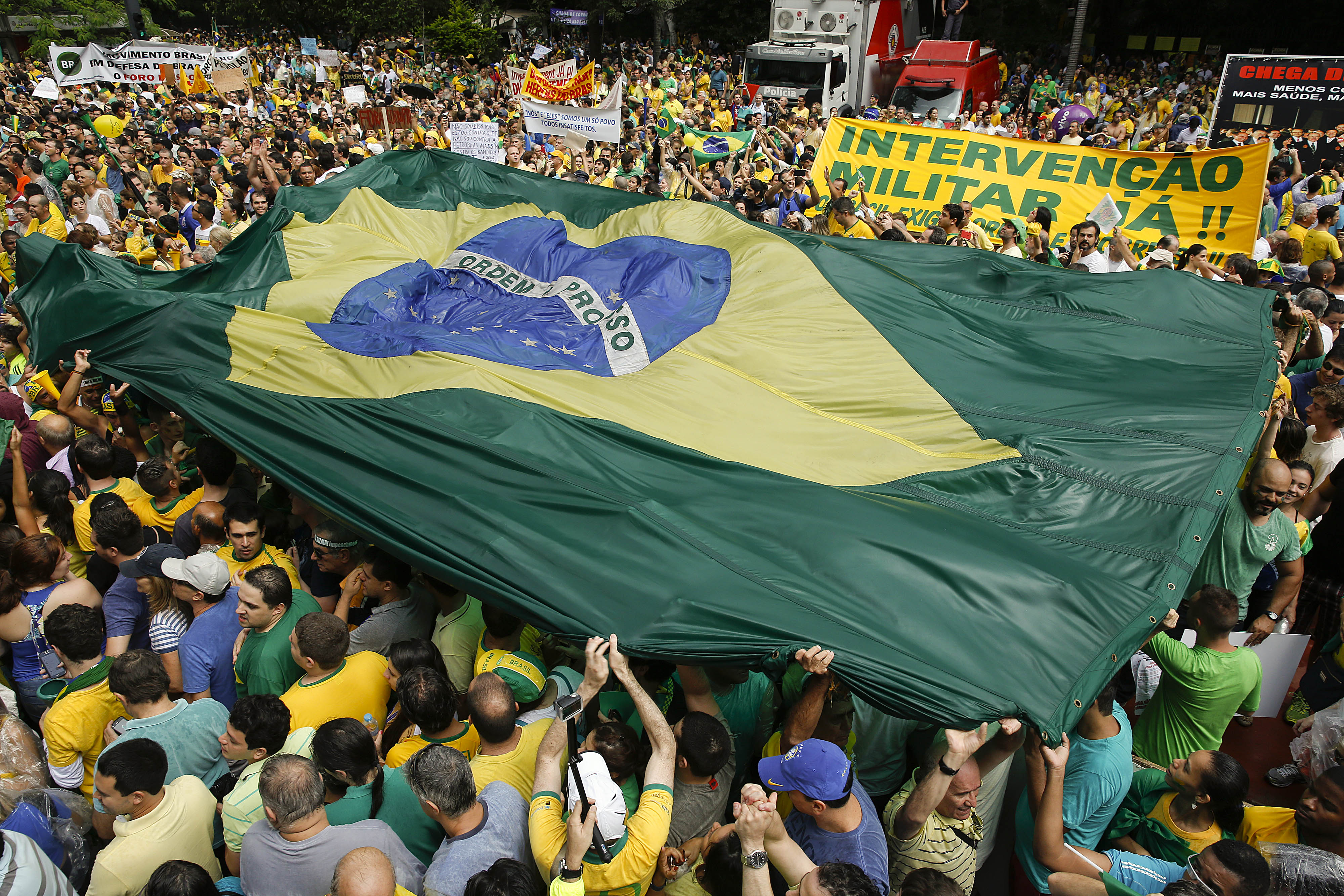 Demonstrators hold a Brazilian flag and a sign that reads in Portuguese "Military intervention now!" during a march demanding the impeachment of Brazil's President Dilma Rousseff in Sao Paulo, Brazil,, March 15, 2015.