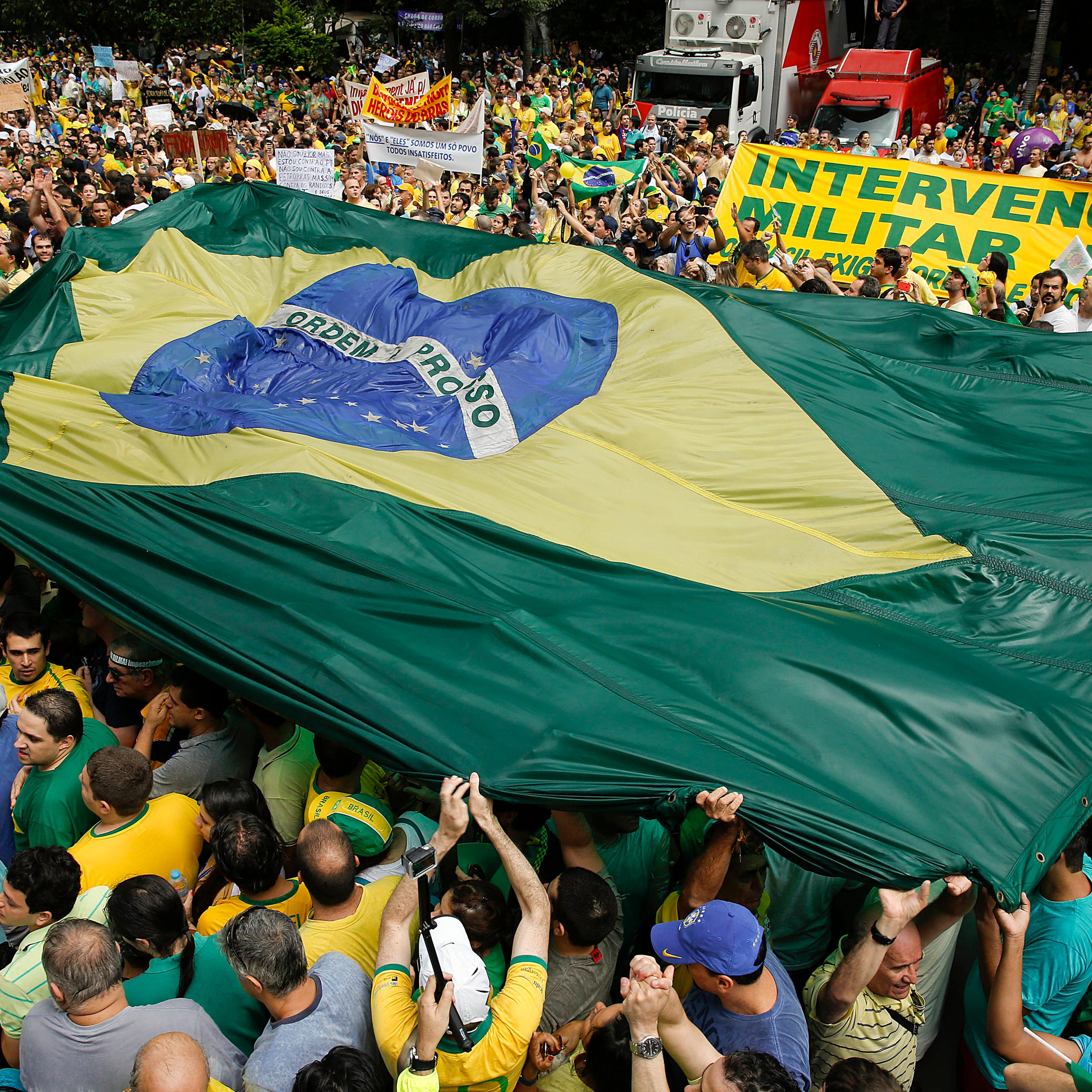 Demonstrators hold a Brazilian flag and a sign that reads in Portuguese "Military intervention now!" during a march demanding the impeachment of Brazil's President Dilma Rousseff in Sao Paulo, Brazil,, March 15, 2015.