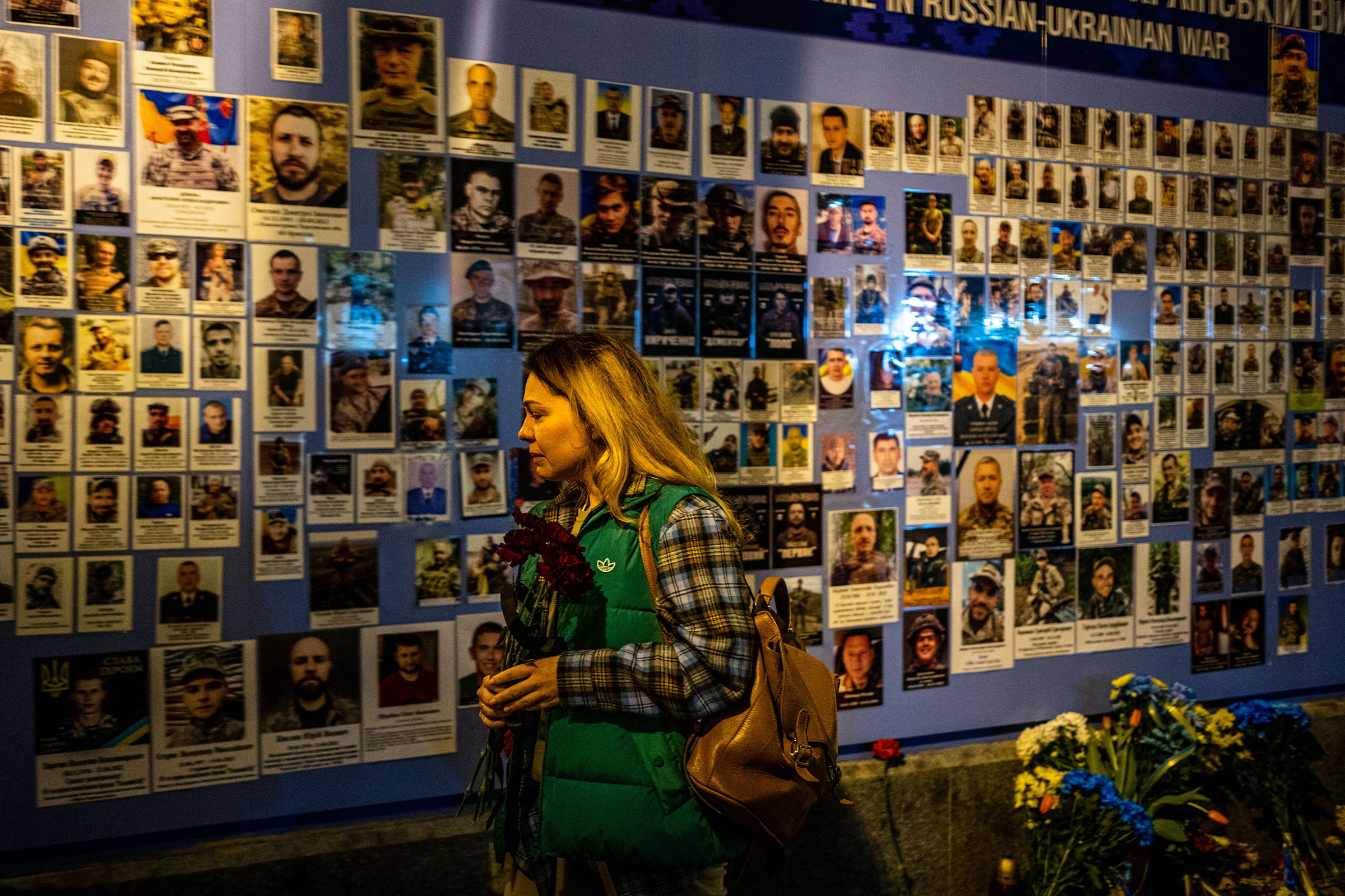 A woman reacts in front of pictures displayed at a Memory Wall of Fallen Defenders of Ukraine in Kyiv on Feb. 24, on the first anniversary of the war. 