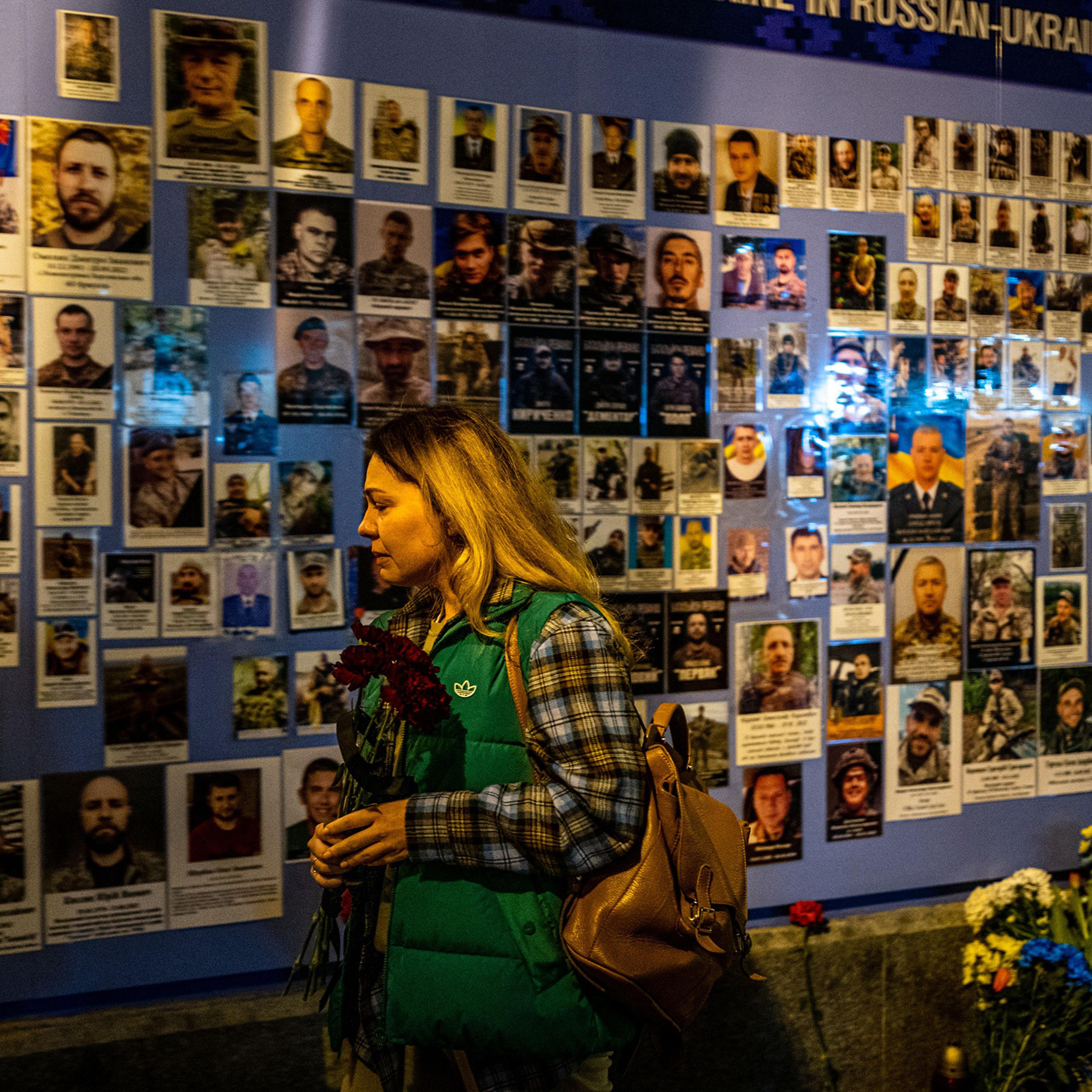 A woman reacts in front of pictures displayed at a Memory Wall of Fallen Defenders of Ukraine in Kyiv on Feb. 24, on the first anniversary of the war.