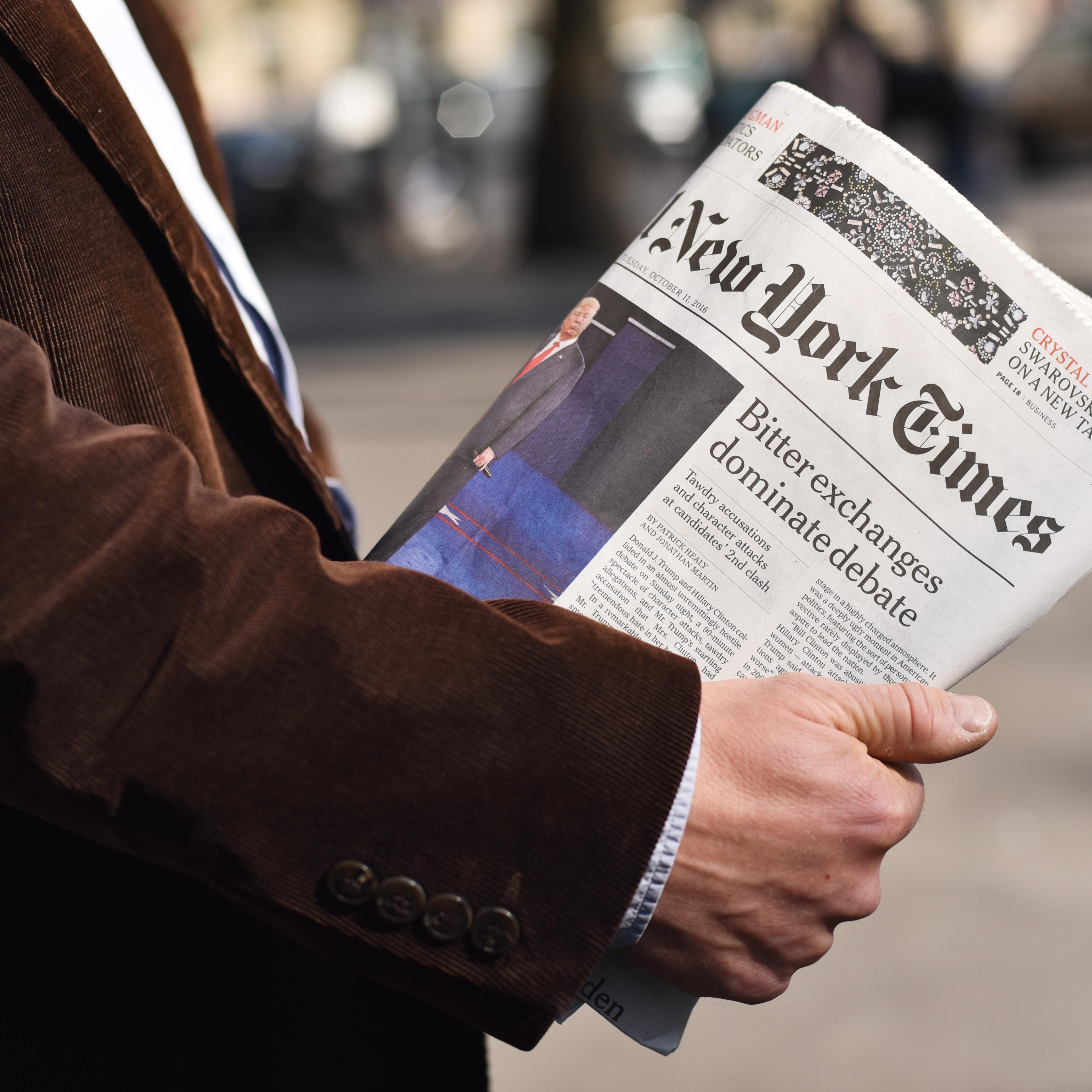 Man holding the New York Times in his hand.