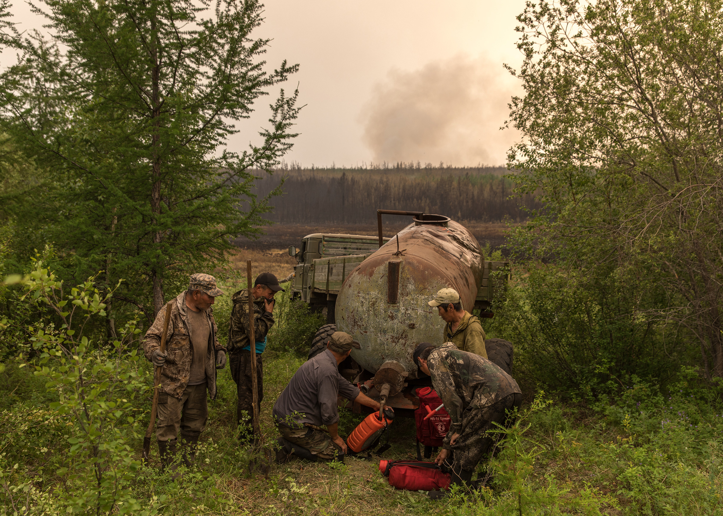 Volunteers fill satchels with water to battle fires near their homes in Magaras, a village in eastern Russia. 