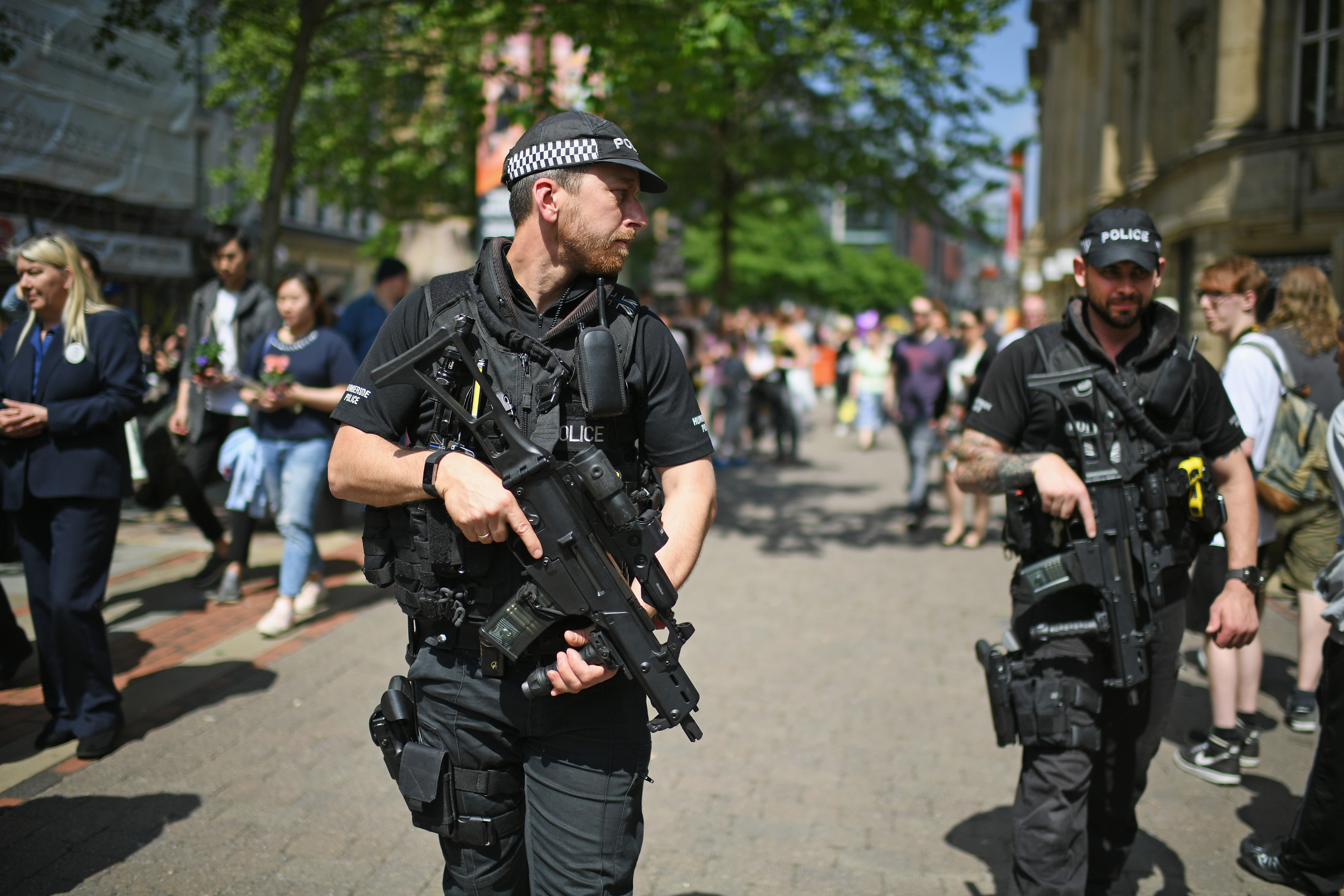 Armed police patrol as members of the public queue to lay flowers in St Ann's Square in memory of those who lost their lives in the Manchester Arena attack, on May 25, 2017 in Manchester