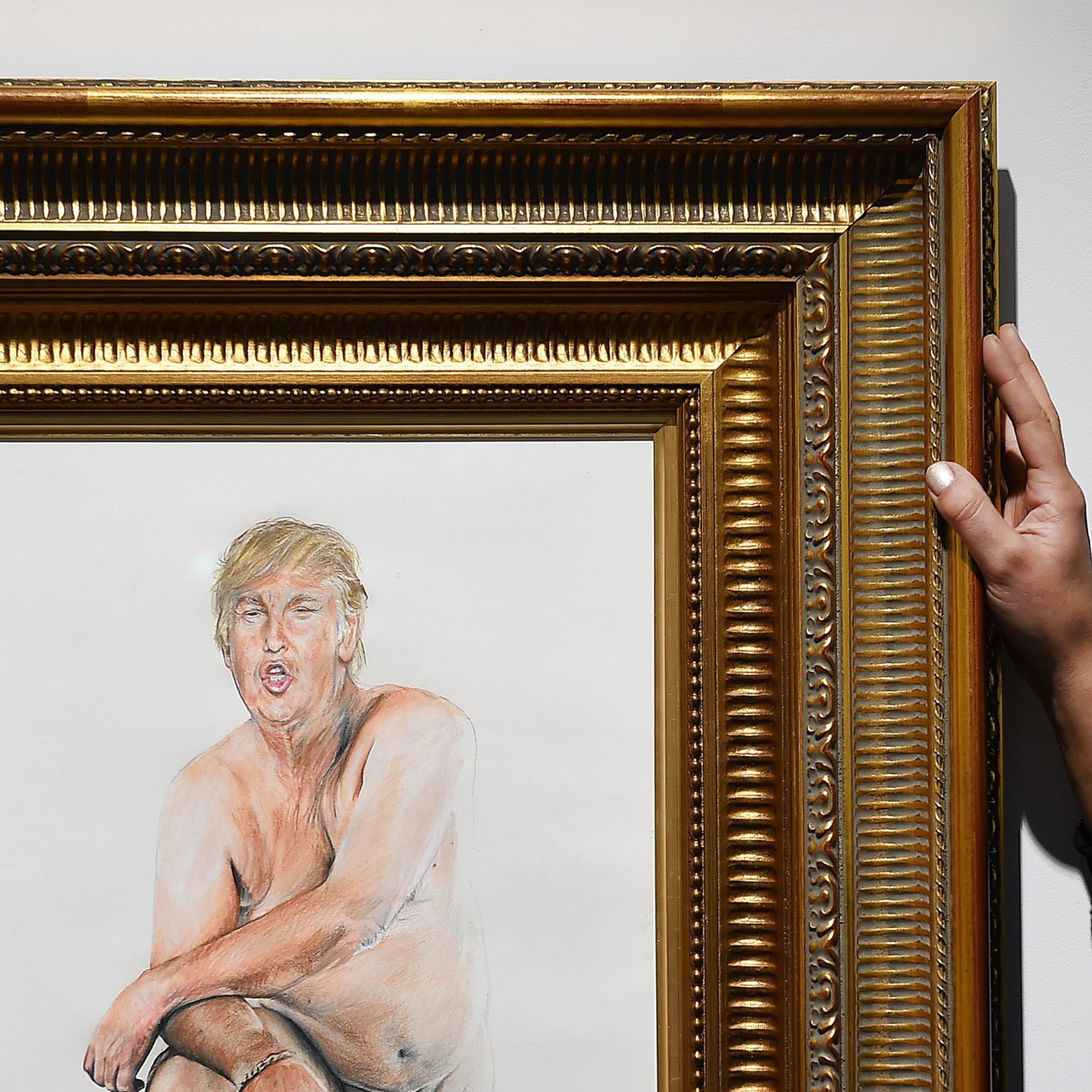 A woman adjusts a painting depicting a naked man with the head of Donald Trump by US artist Illma Gore at the Maddox Gallery in London, April 11, 2016.