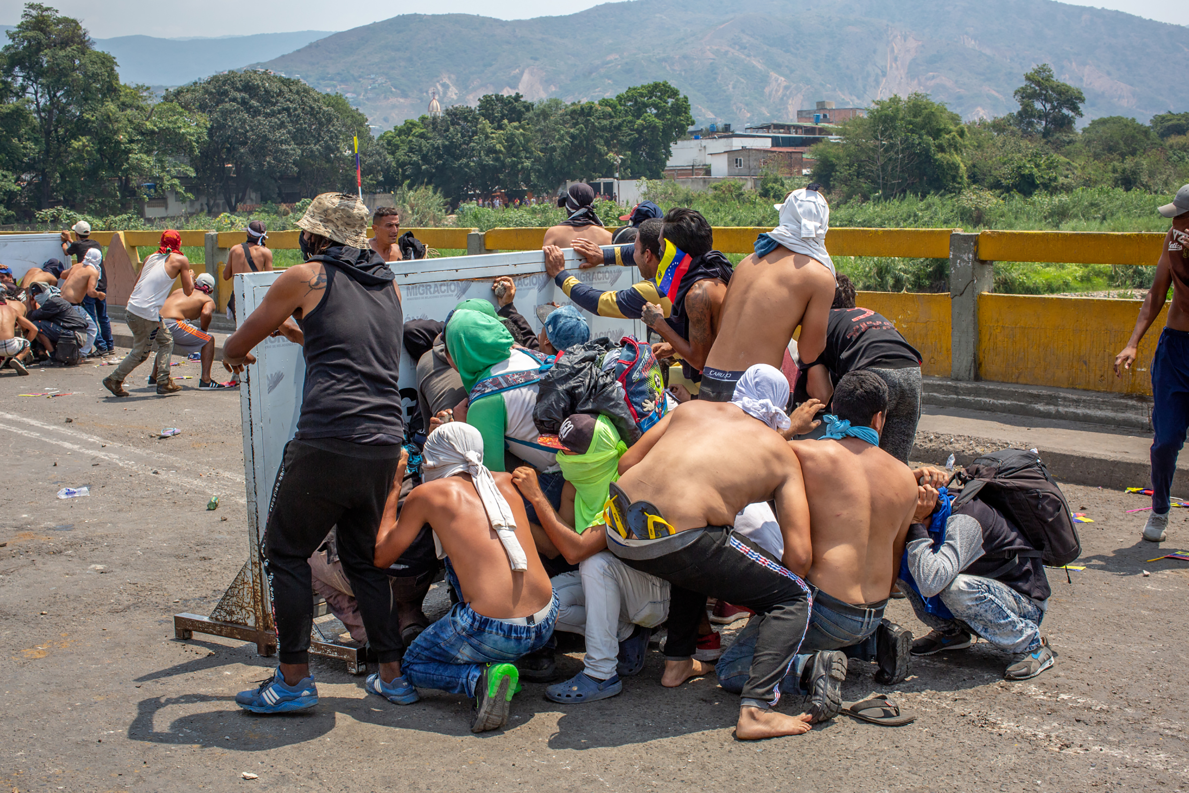 A group of demonstrators take cover during a clash with Venezuelan national police officers on the Simón Bolívar International Bridge, which connects Colombia and Venezuela, near Cúcuta, on Feb. 23, 2019.