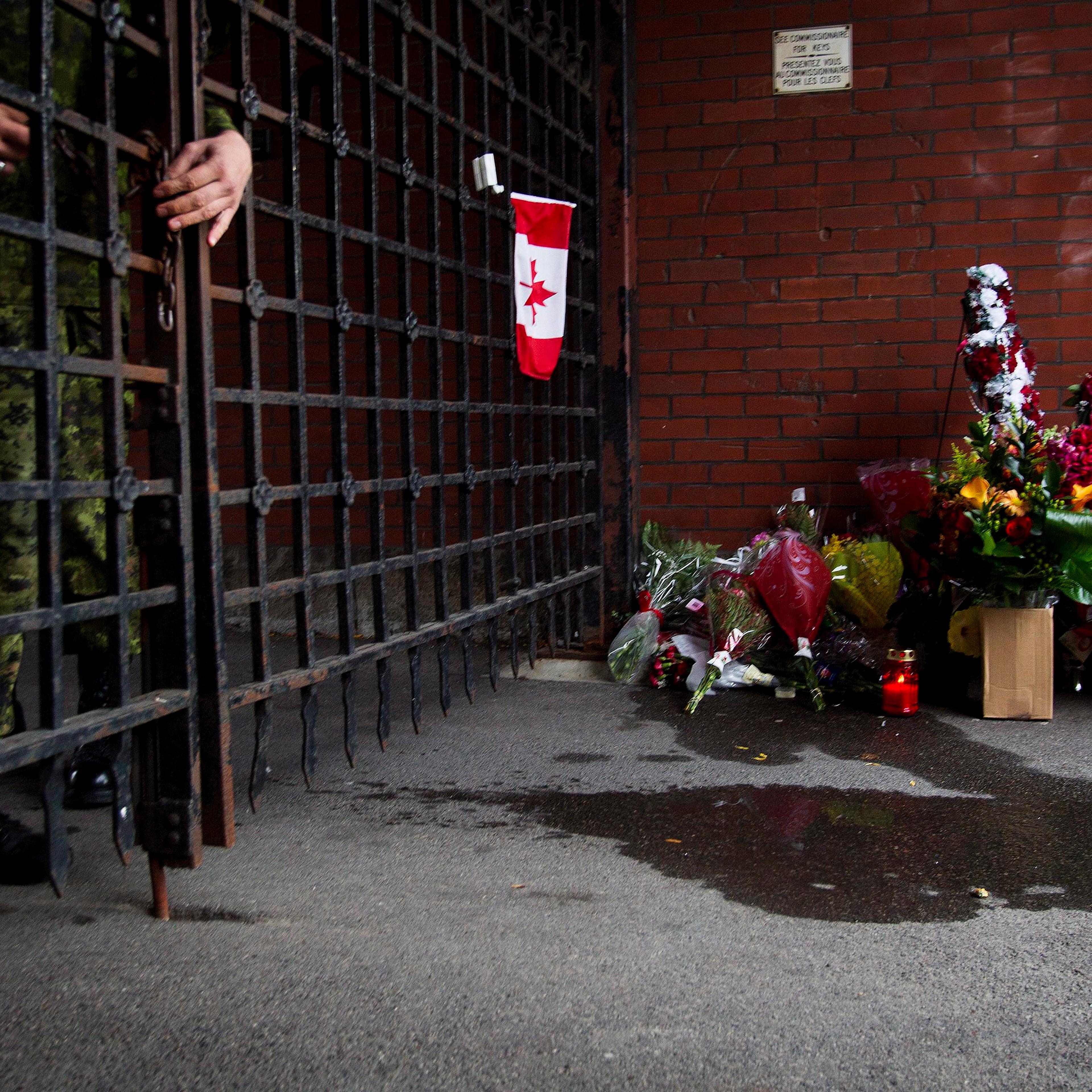 A soldier locks the gates as flowers are placed at a memorial outside the gates of the John Weir Foote Armory, the home of the Argyll and Sutherland Highlanders of Canada in Hamilton, Ontario on Oct. 22, 2014, in memory of Canadian soldier Nathan Cirillo