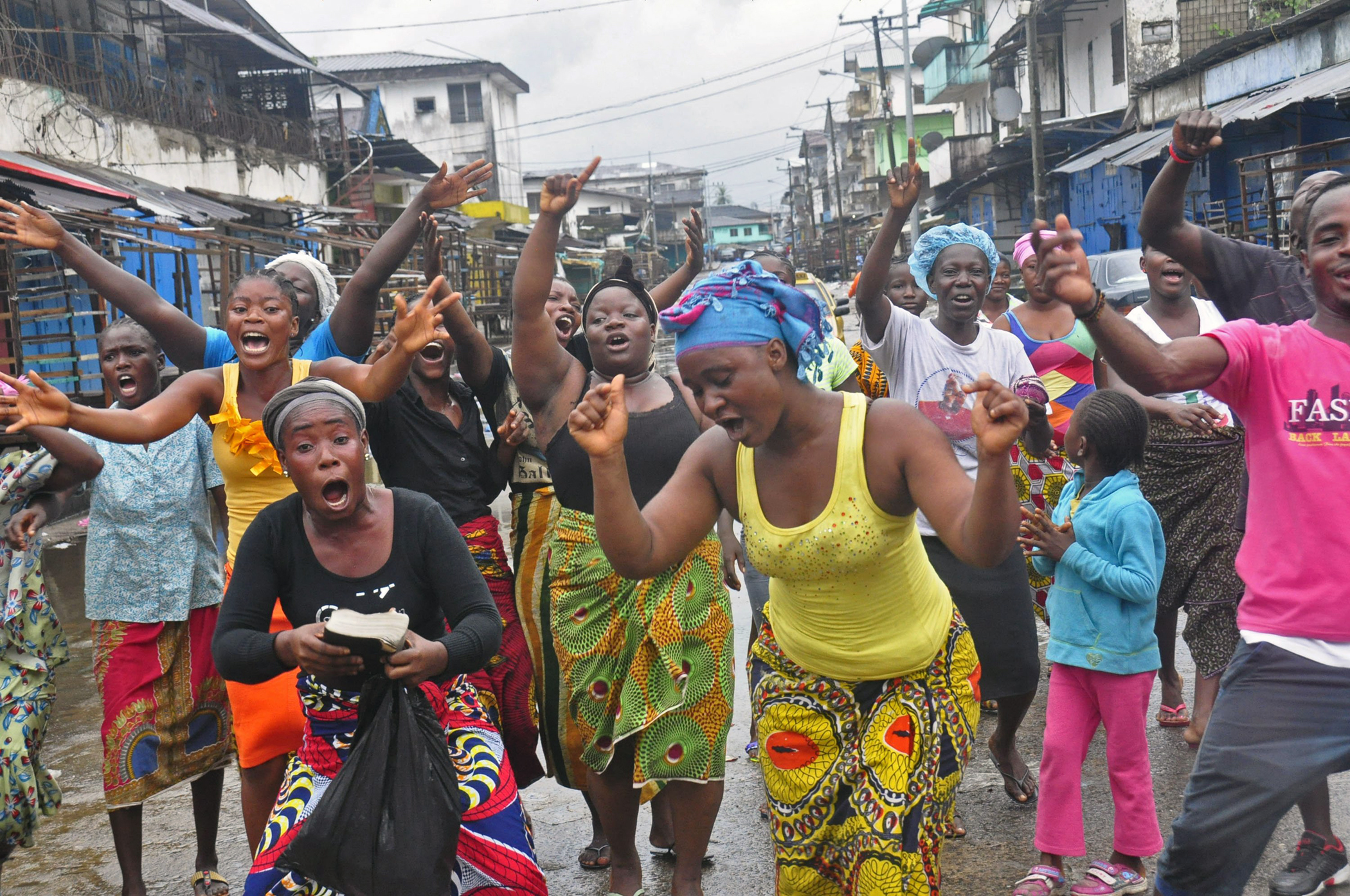 People celebrate in a street outside of West Point slum in Monrovia, Liberia, Aug. 30, 2014. Crowds cheer and celebrate in the streets after Liberian authorities reopened a slum where tens of thousands of people were barricaded amid the countryís Ebola o
