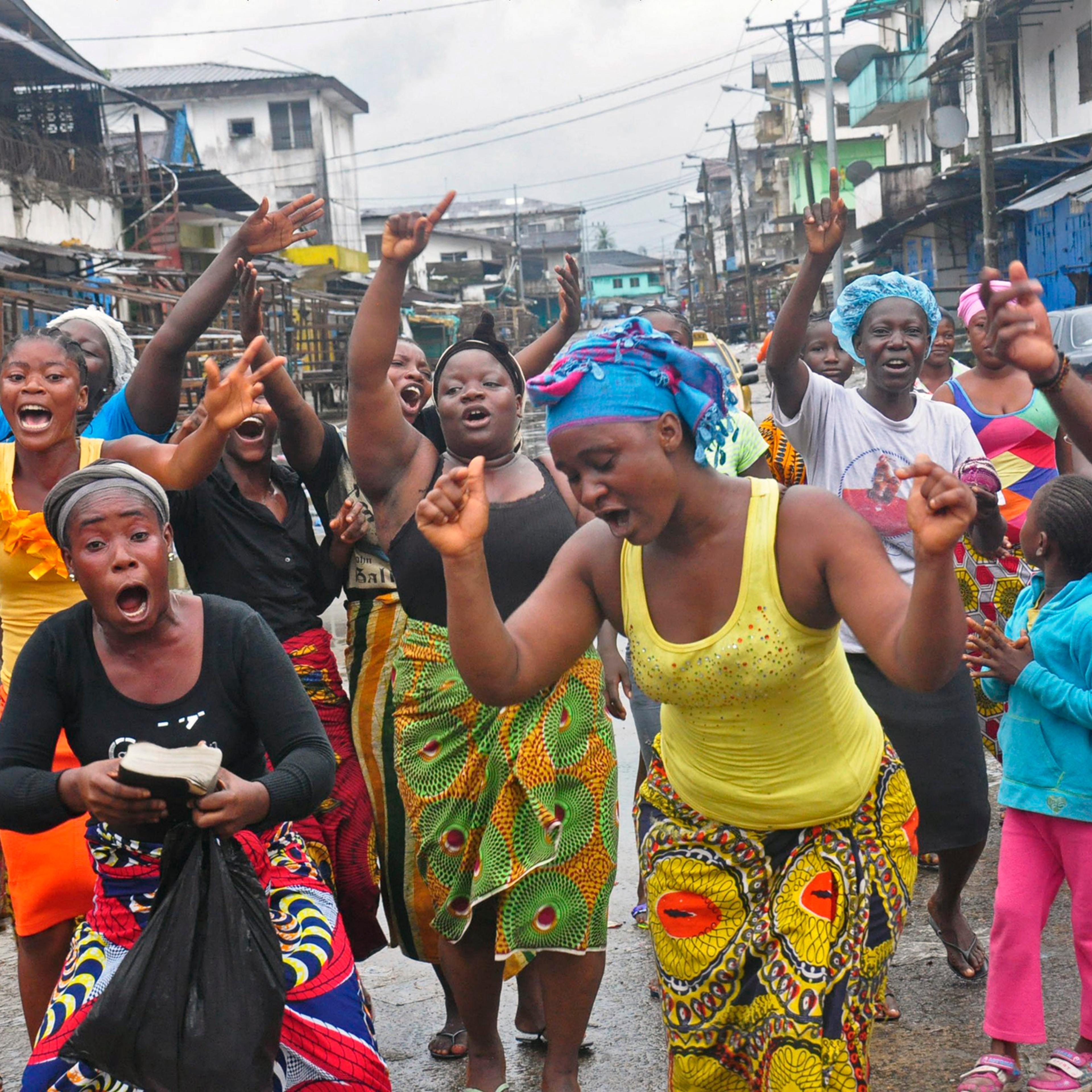 People celebrate in a street outside of West Point slum in Monrovia, Liberia, Aug. 30, 2014. Crowds cheer and celebrate in the streets after Liberian authorities reopened a slum where tens of thousands of people were barricaded amid the countryís Ebola o
