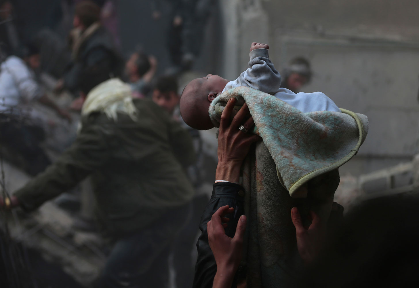 Men hold up a baby saved from under rubble, who survived an airstrike in the Duma neighbourhood of Damascus