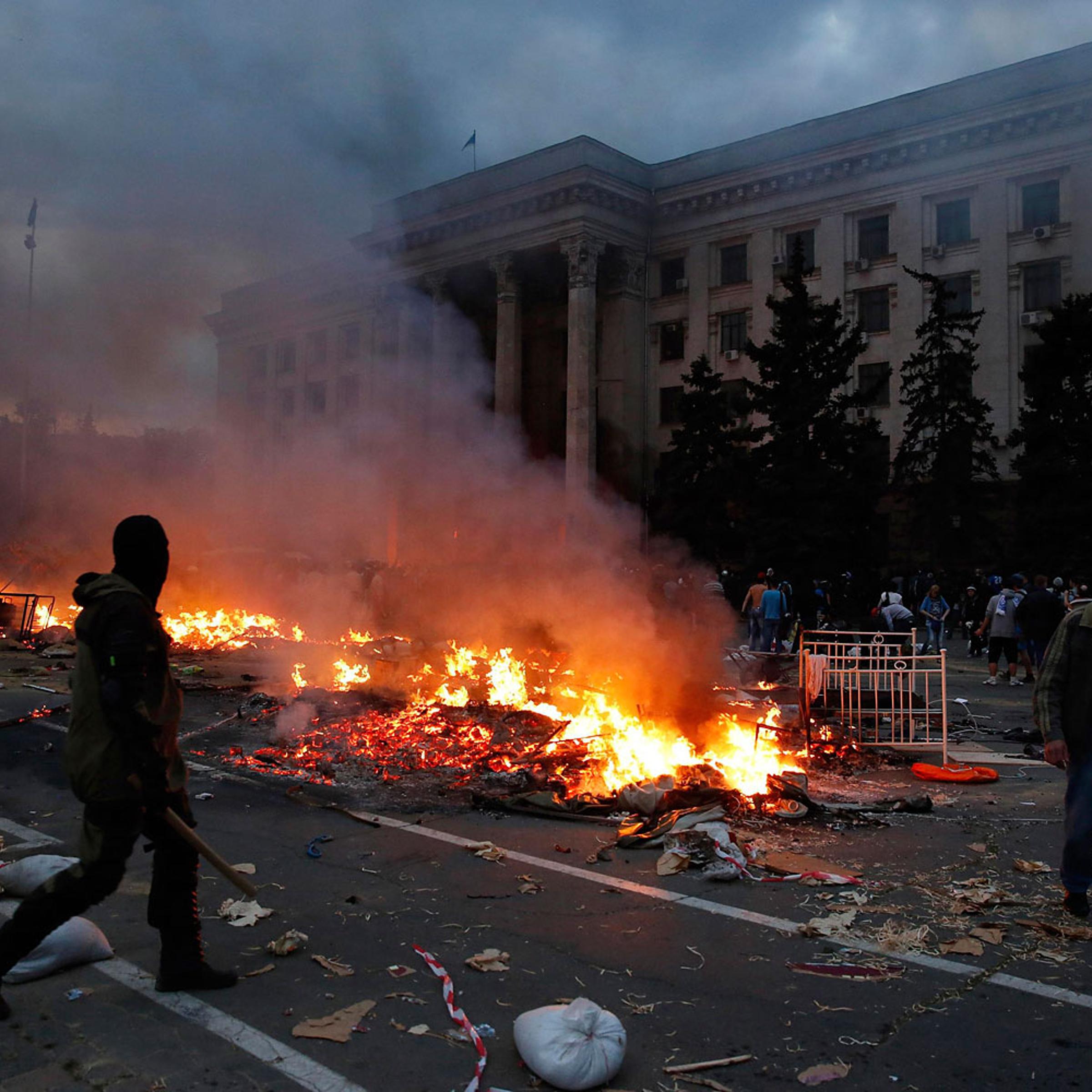 A protester walks past a burning pro-Russian tent camp near the trade union building in Odessa
