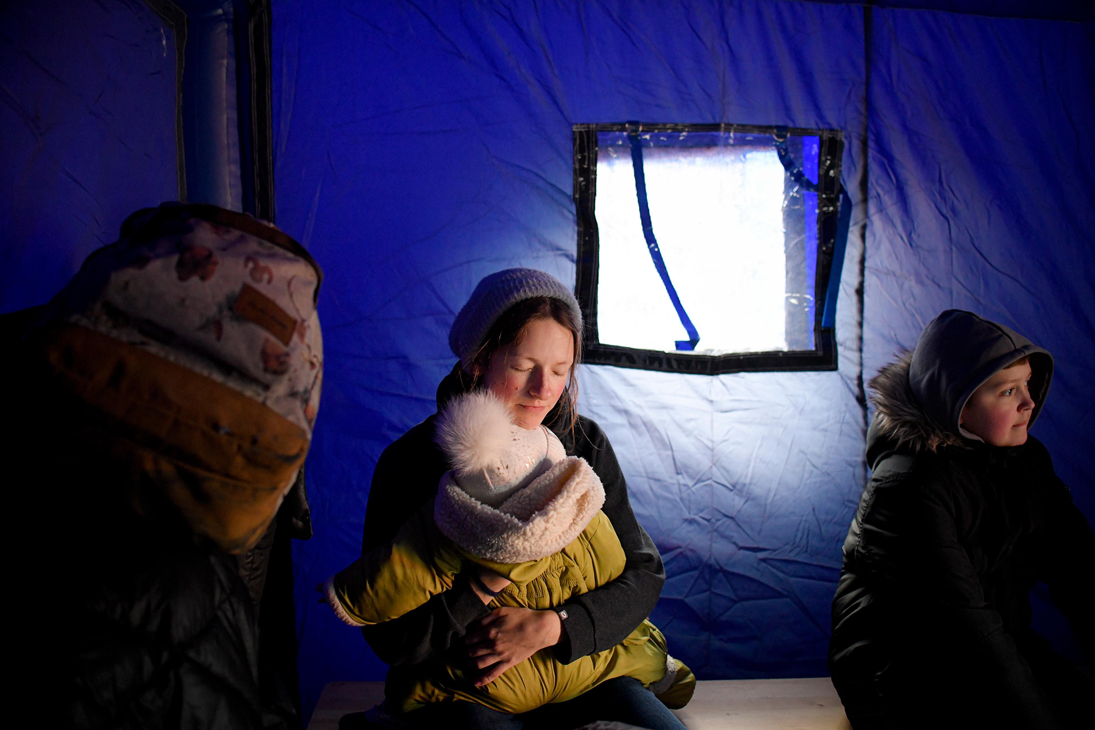 A refugee fleeing Ukraine holds her baby as she sits in a tent at the border in Siret, Romania on Feb. 26