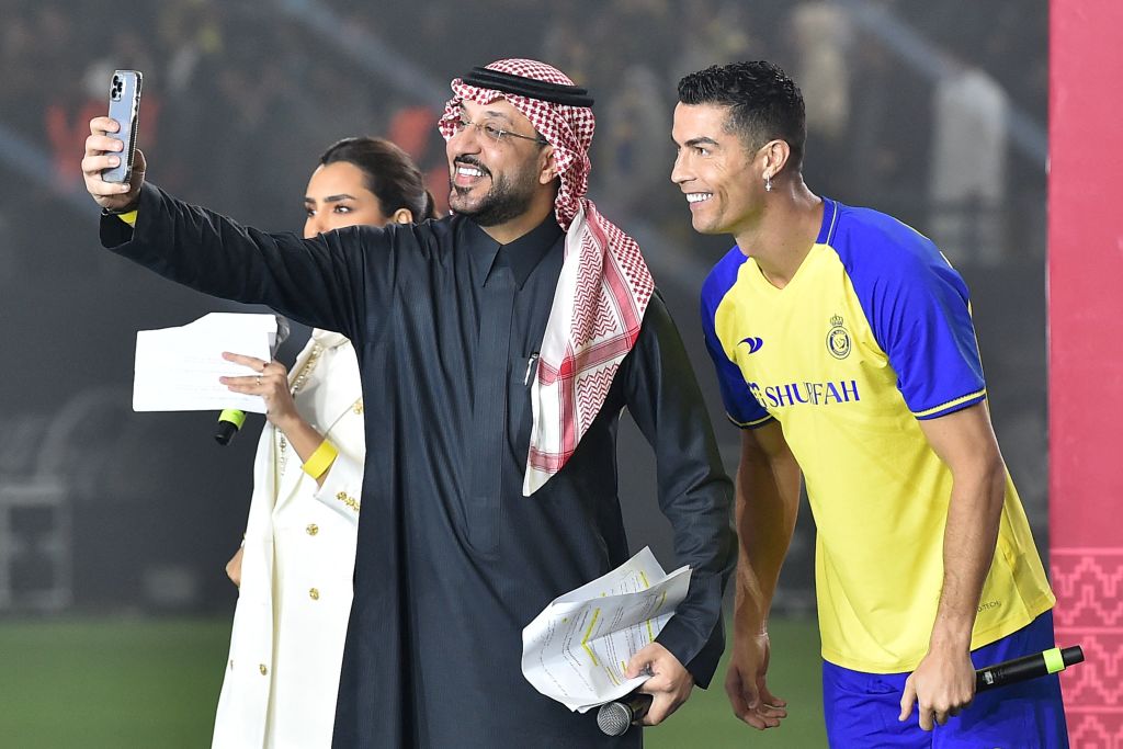 Al-Nassr's new Portuguese forward Cristiano Ronaldo (R), wearing a cross earing, poses for a selfie with the presenters during his unveiling at the Mrsool Park Stadium in the Saudi capital Riyadh on Jan. 3, 2023.