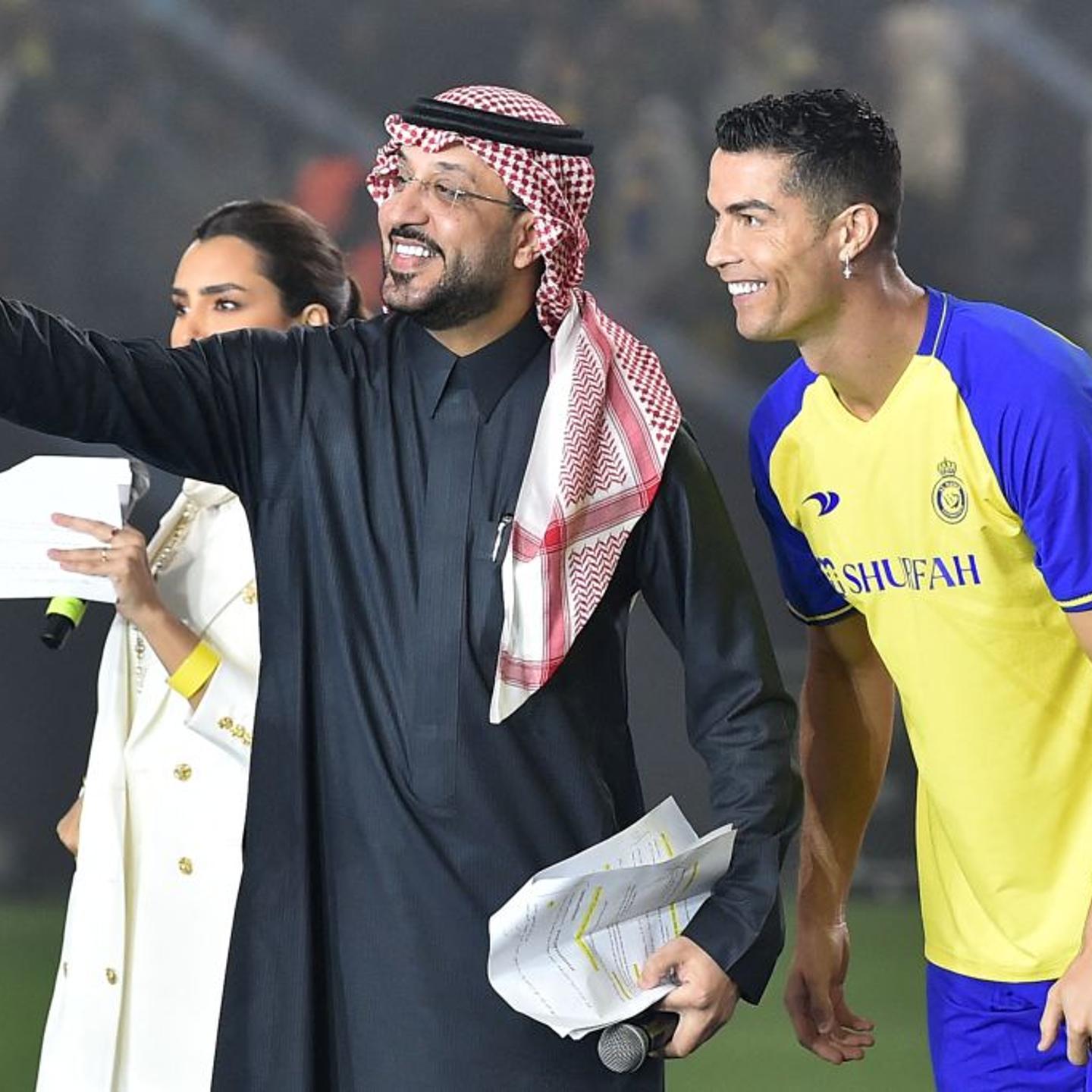 Al-Nassr's new Portuguese forward Cristiano Ronaldo (R), wearing a cross earing, poses for a selfie with the presenters during his unveiling at the Mrsool Park Stadium in the Saudi capital Riyadh on Jan. 3, 2023.