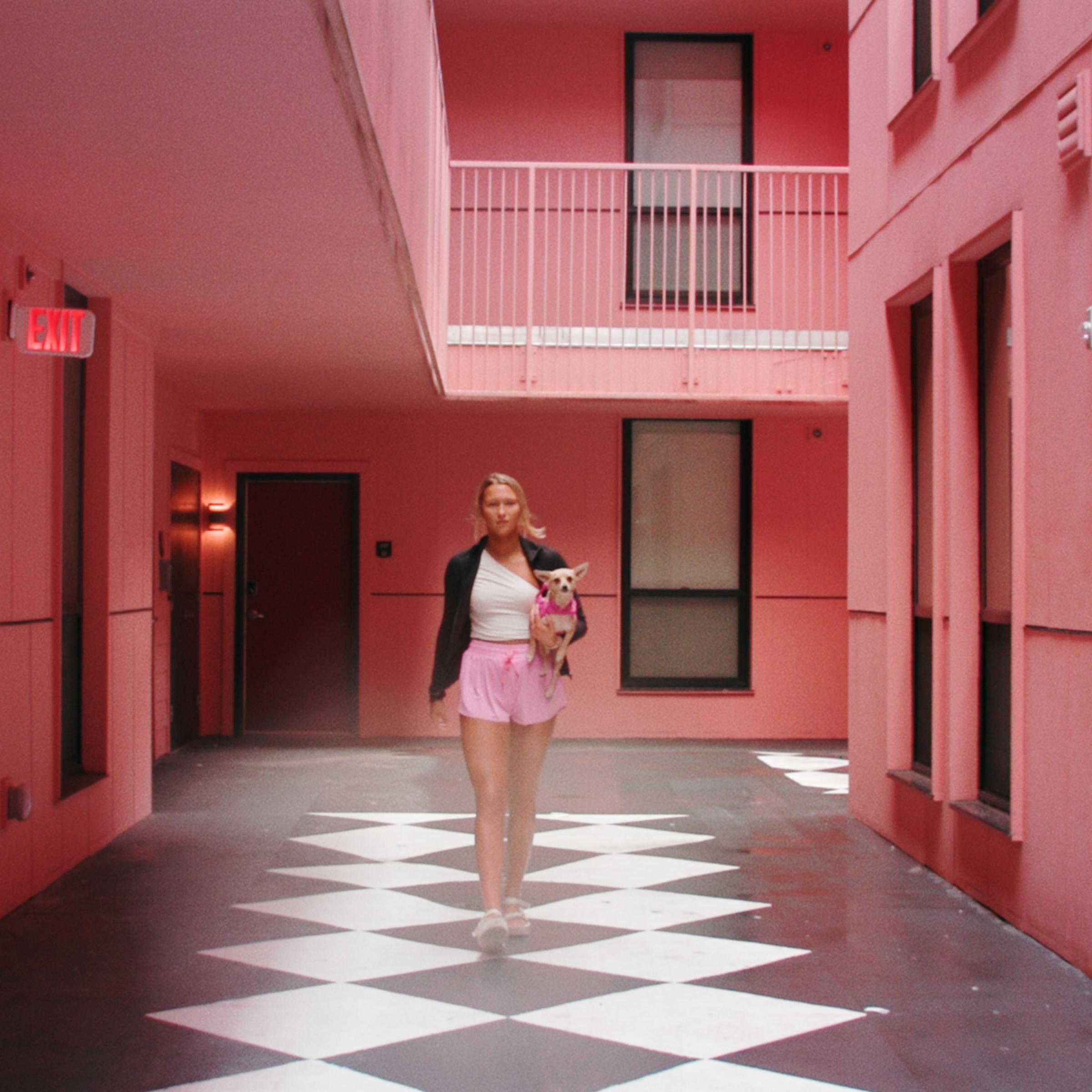 University of Alabama student walking through a pink courtyard