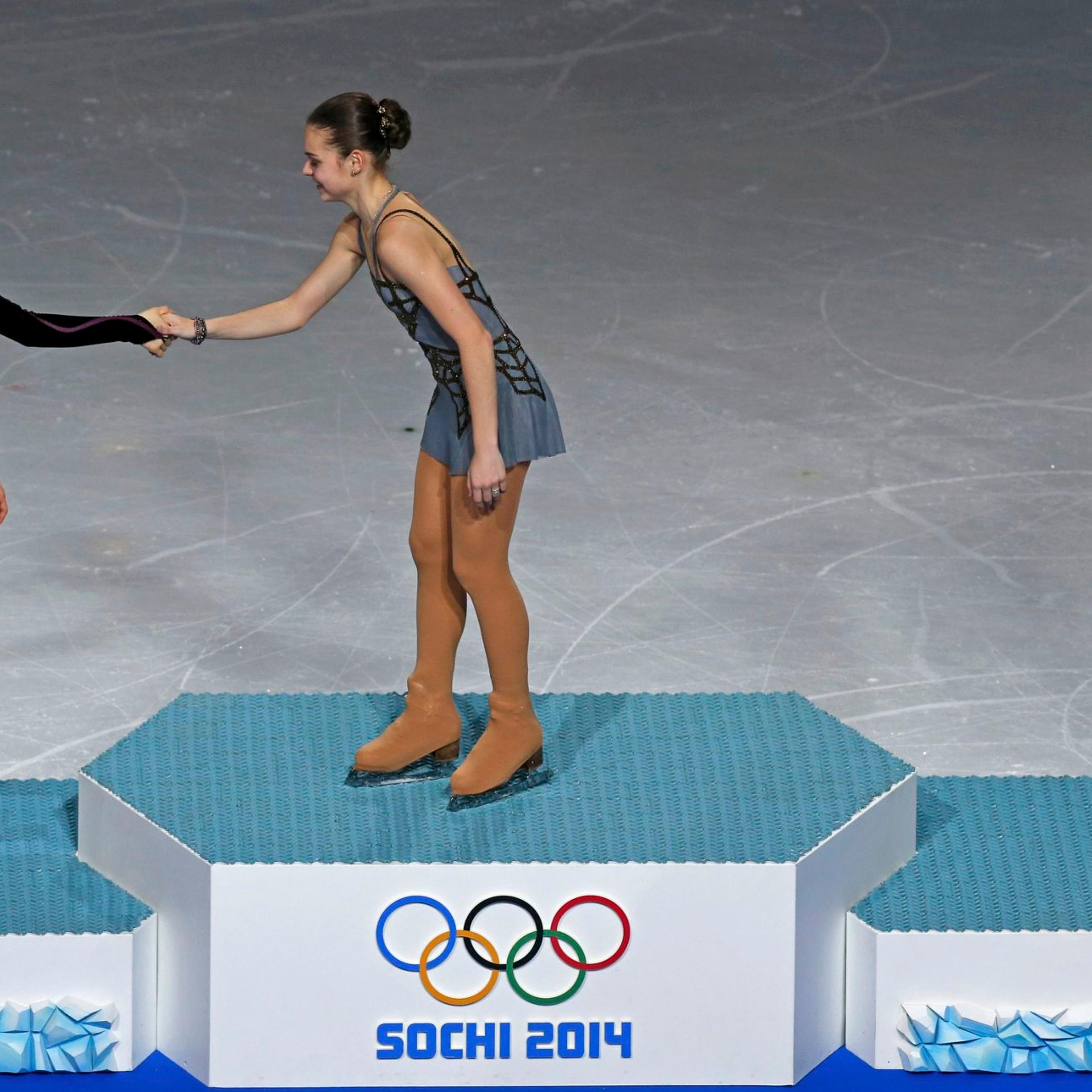 First-placed Russia's Adelina Sotnikova (C) shakes hands with second-placed South Korea's Kim Yuna (L) as third-placed Italy's Carolina Kostner looks on, on the podium after the figure skating women's free skating program.