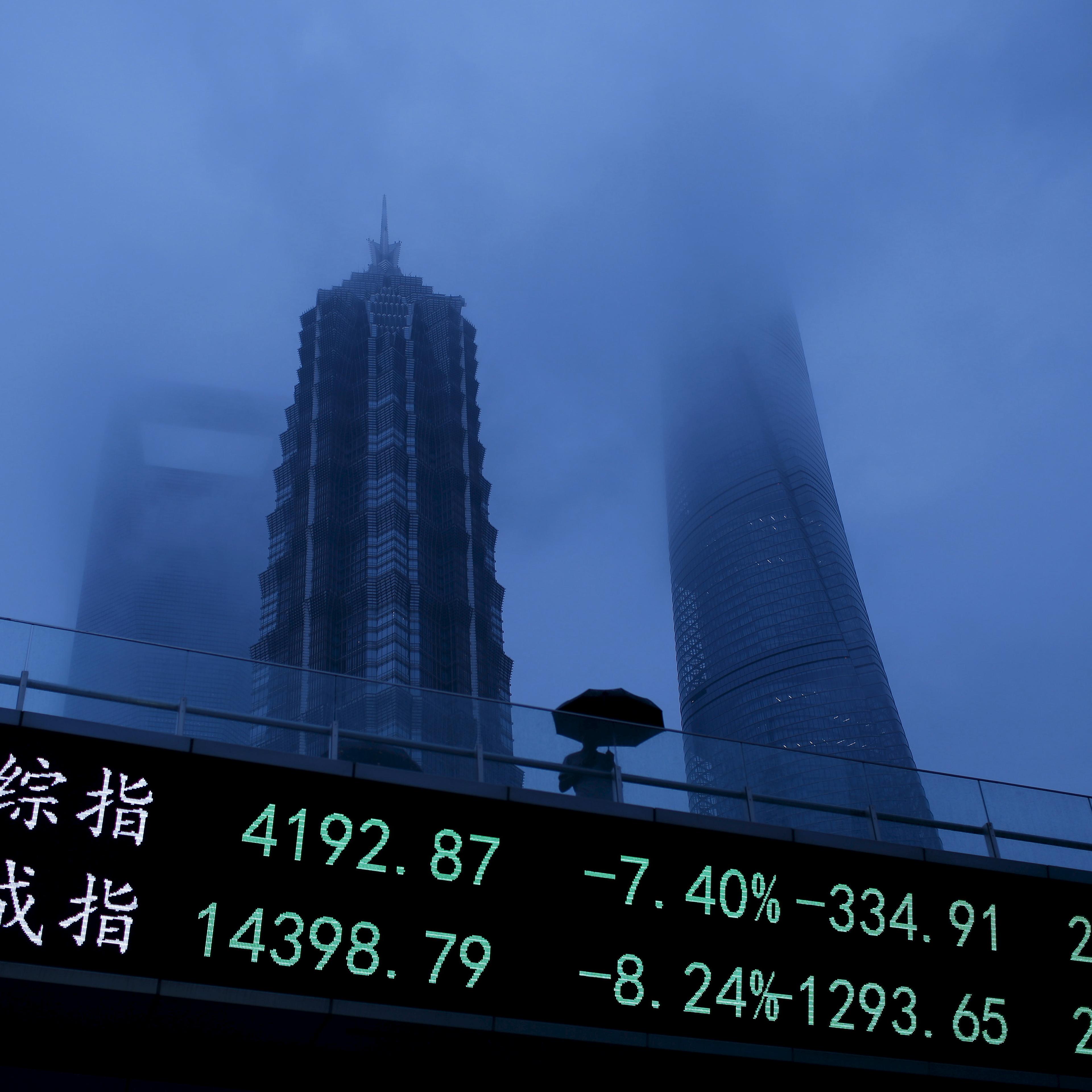 A man walks past an electronic board showing the benchmark Shanghai and Shenzhen stock indices, on a pedestrian overpass at the Pudong financial district in Shanghai