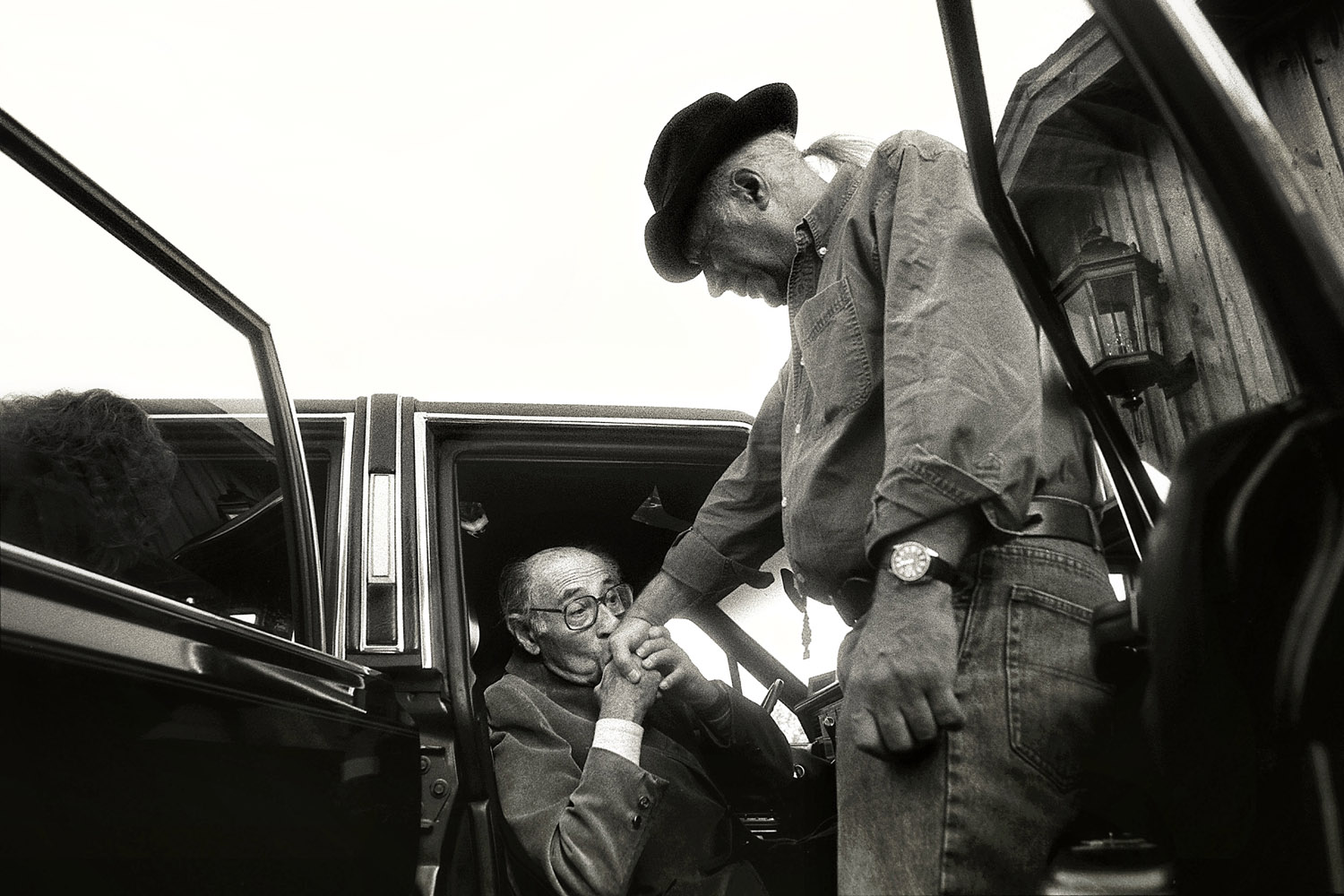 <b>1992: Rick Loomis</b>
<br /><br />
Alfred Eisenstaedt kisses the hand of Eddie Adams after speaking at the workshop in 1992.
<br /><br />
<i>"The third time was a charm when I applied to the Eddie Adams
Workshop as a student from Western Kentucky University. My first two applications were met with rejection but the experience proved worth the wait. The workshop was intense with a roster full of industry heavies that I had only ever heard about. Speaker after speaker came to the podium sharing their work, their insights, themselves.<br /><br />One of those legends was Alfred Eisenstaedt. When he finished his speech and slowly headed out of the barn, something compelled me to sneak out behind him while everyone else turned their attention to the next speaker. Eddie Adams had also come outside to see him off. Before closing the car door, 'Eisie' kissed Eddie's hand. I was privileged to witness these two giants in the world of photography pay homage to one another.<br /><br />In that m