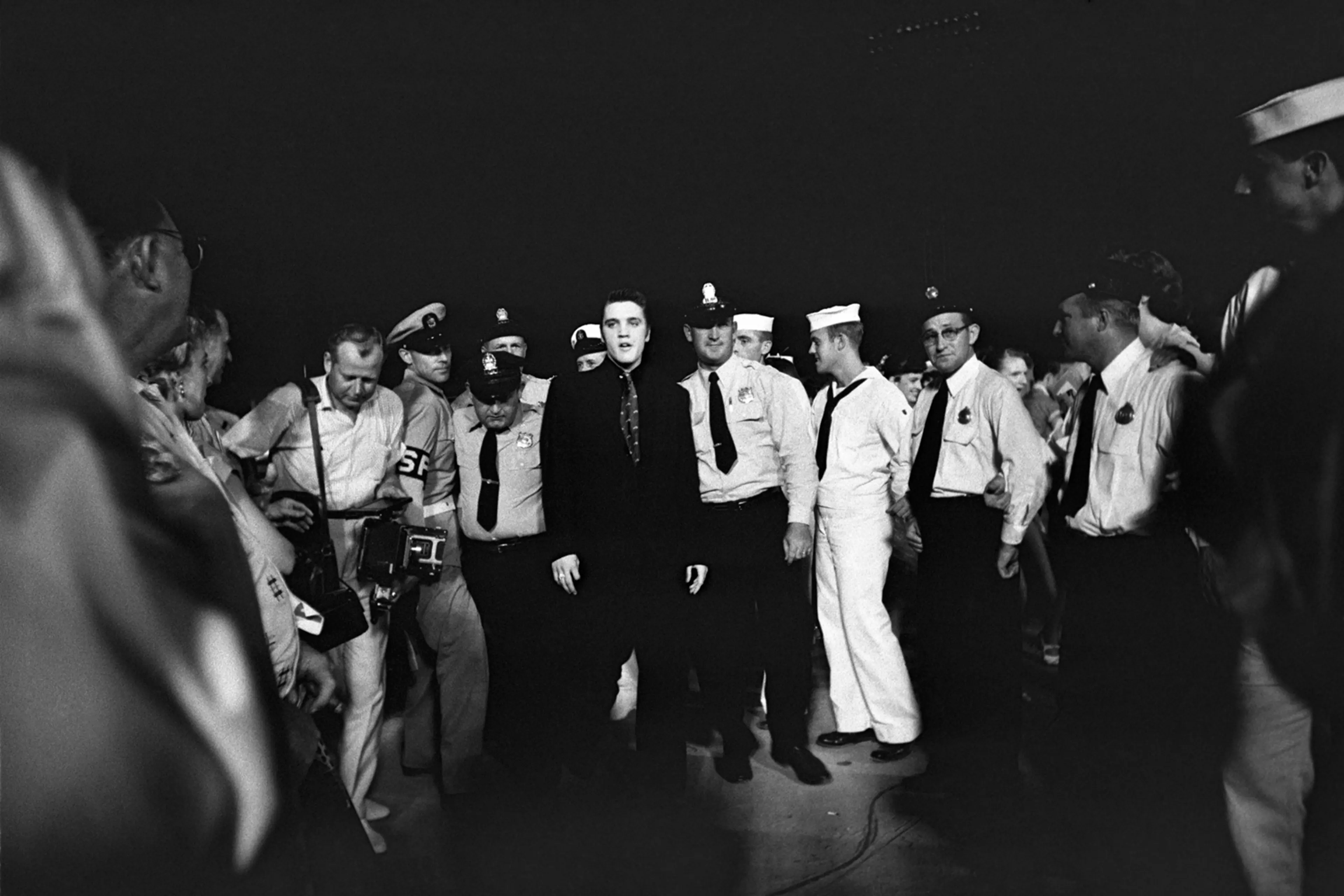July 4, 1956. Russwood Park, Memphis. Elvis is entering the stadium escorted by the local police and fire department, but also by the Shore Police of the Navy. This was Elvis' first charitable benefit show, with proceeds going to The Cynthia Milk Fund and the Variety Club’s Home for Convalescent Children.
