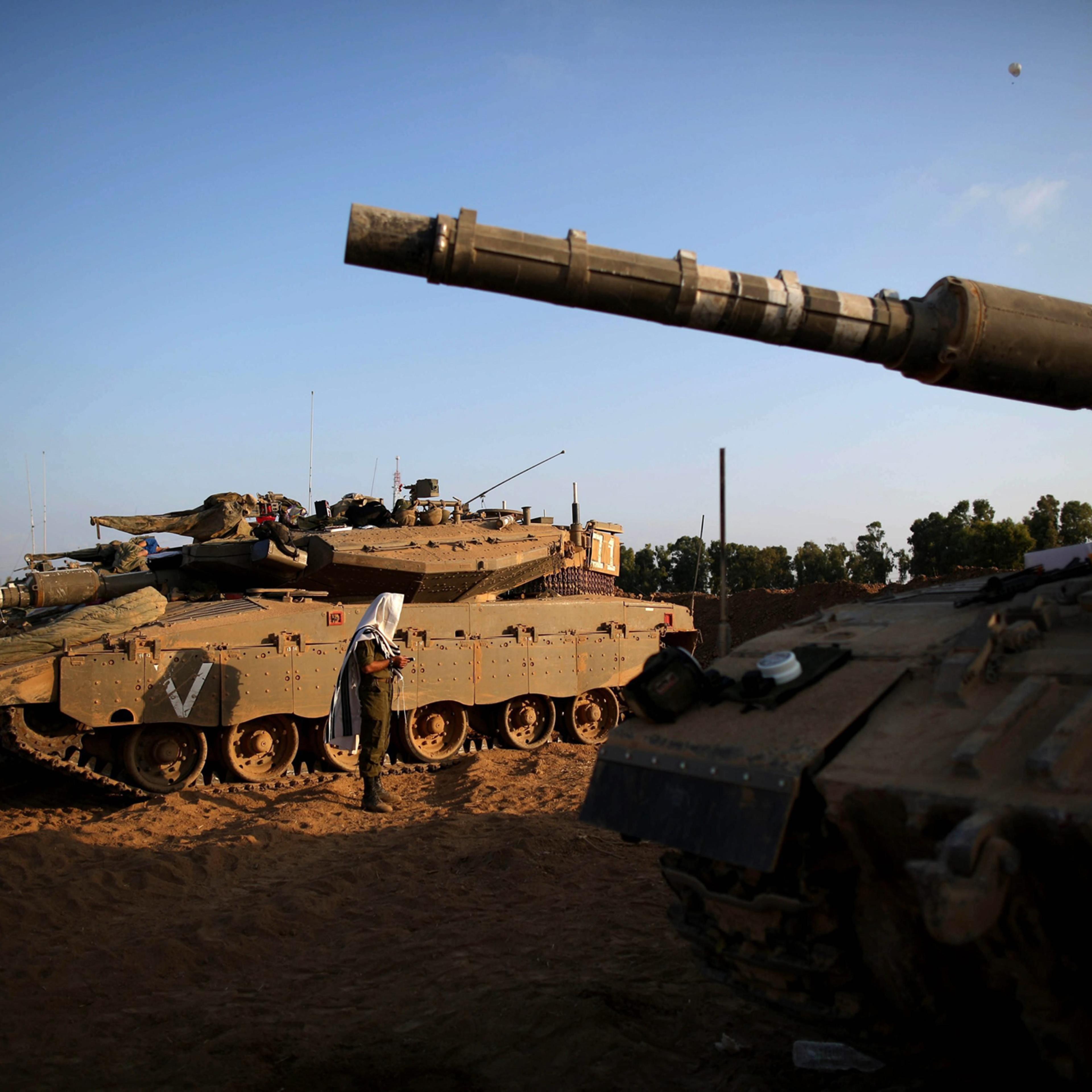 An Israeli soldier prays next to Merkava tanks at an unspecified location near the Israeli border with the Gaza Strip, Aug. 6, 2014.