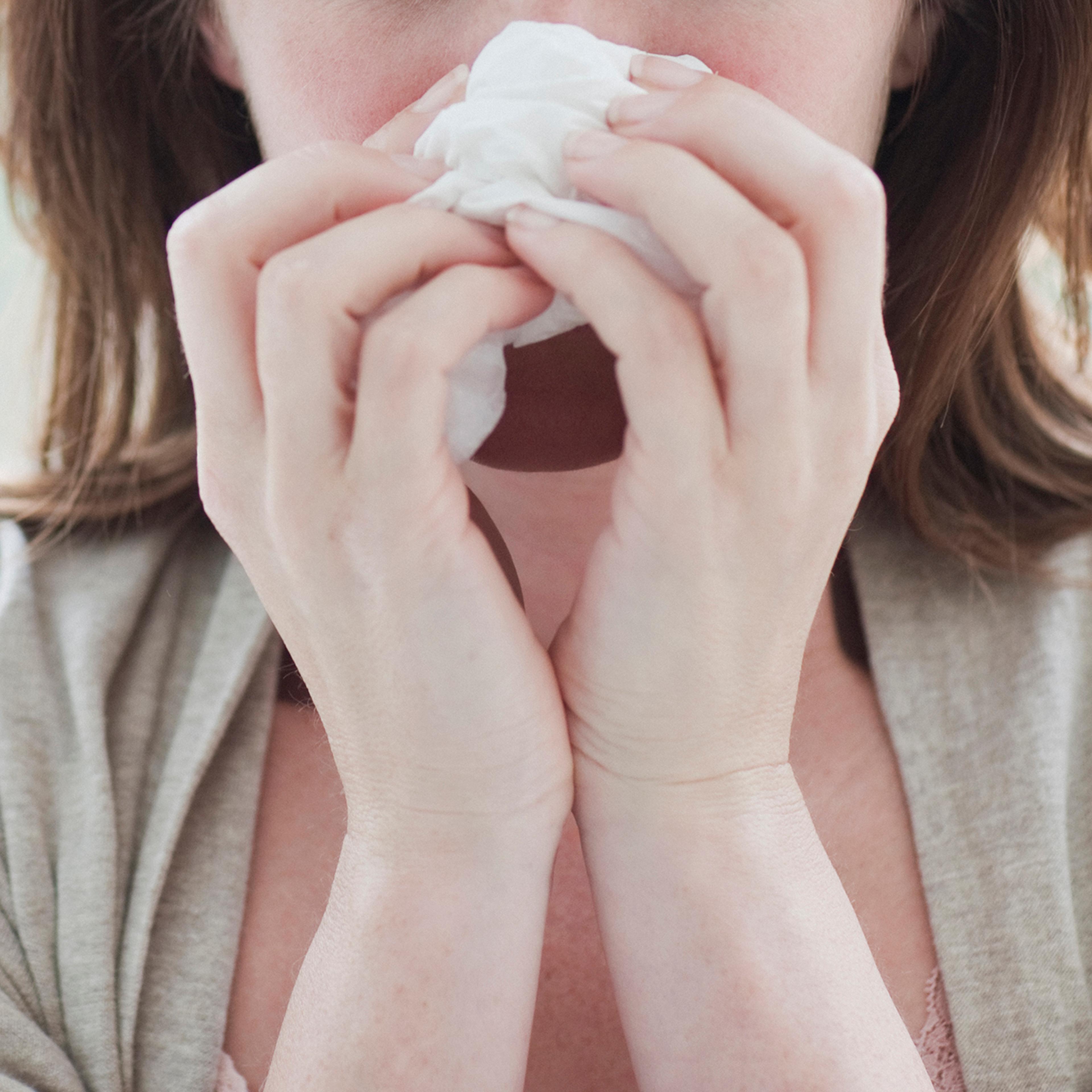 Sick woman wiping her nose