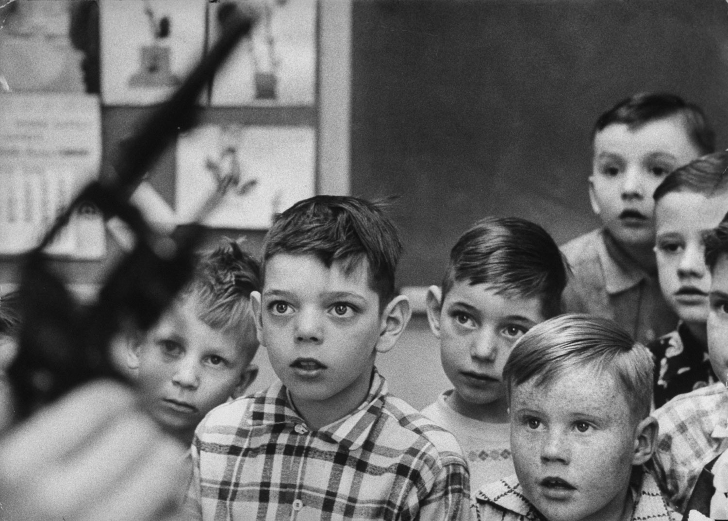 Wide-eyed fascination is displayed by boys as Rankin holds his revolver with the cylinder opened to show them there are no shells in it.