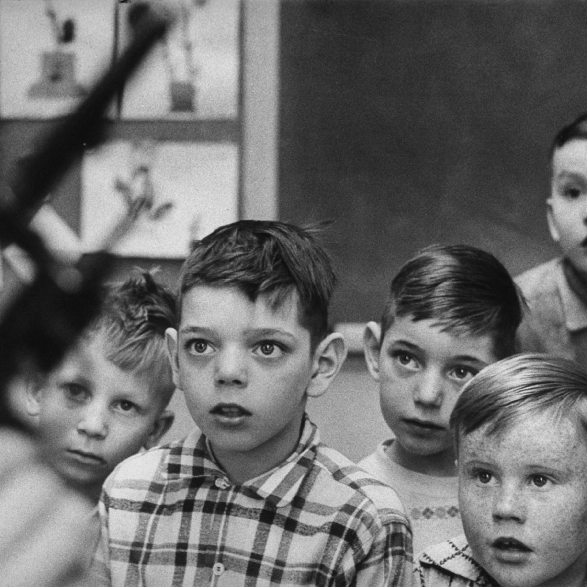 Wide-eyed fascination is displayed by boys as Rankin holds his revolver with the cylinder opened to show them there are no shells in it.