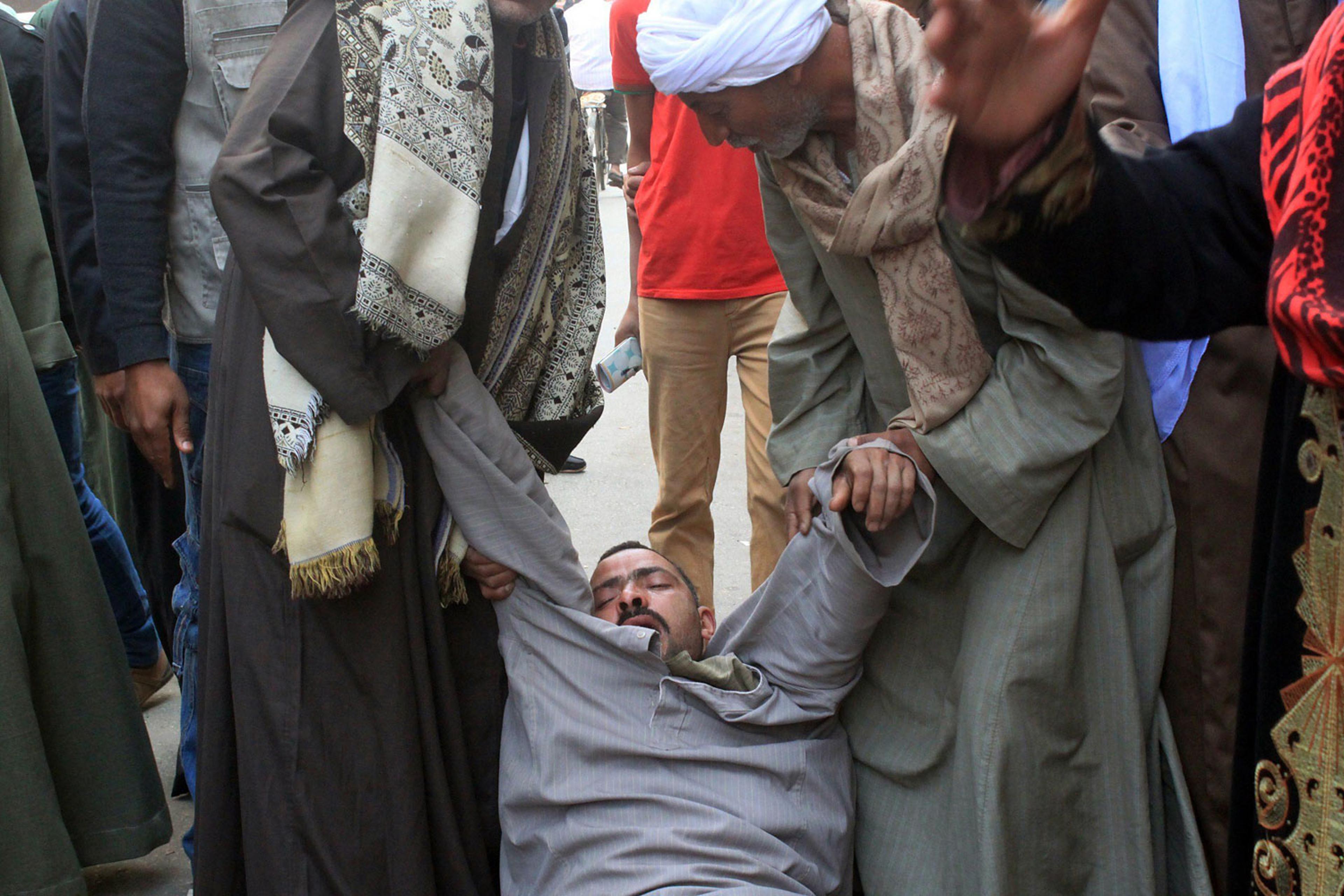 A relative of a supporter of Egyptian ousted Islamist president Mohamed Morsi is supported as he faints outside the courthouse on March 24, 2014 in the central Egyptian city of Minya, after the court ordered the execution of 529 Morsi supporters after on
