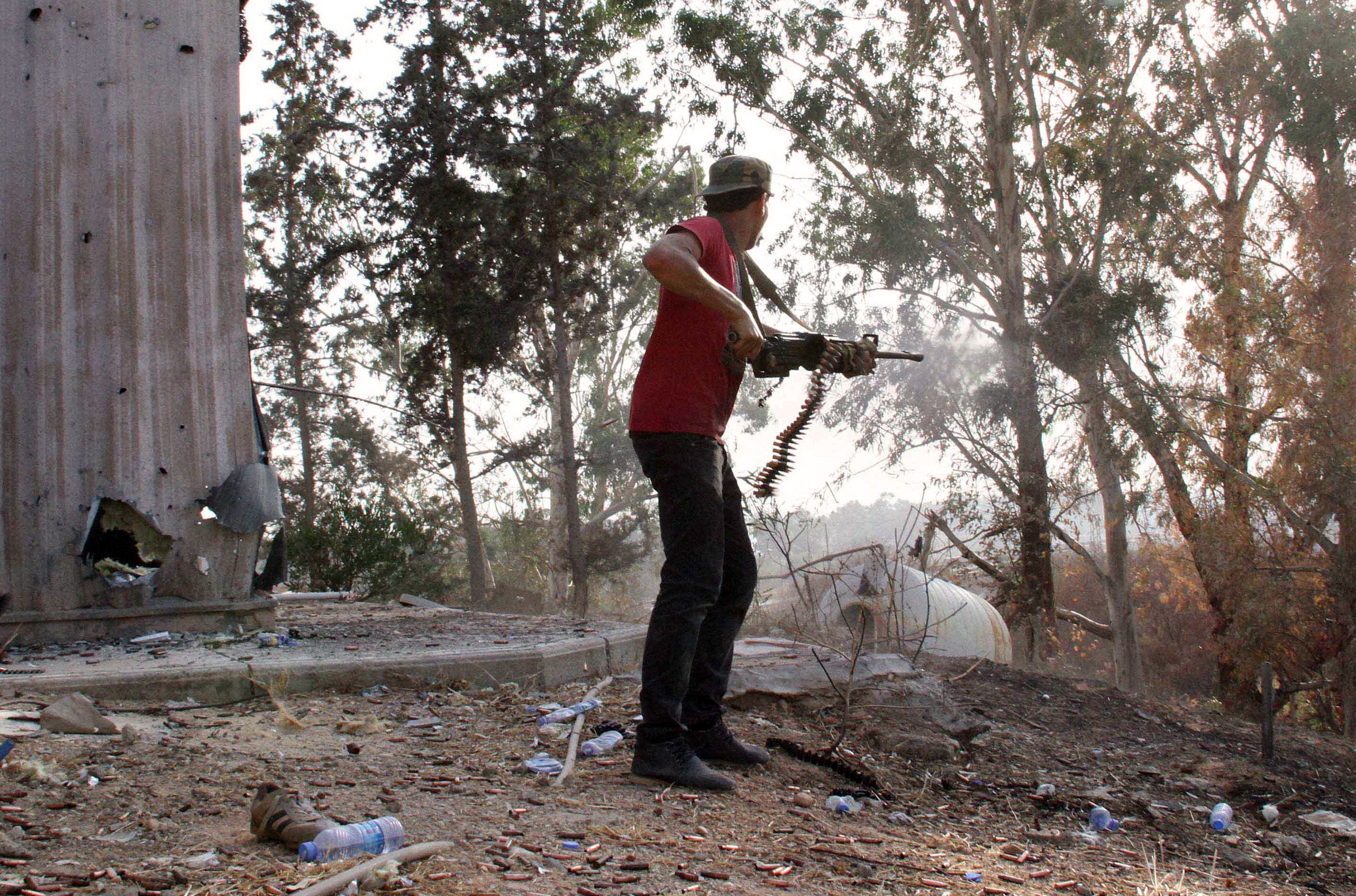 A man fires a weapon during fightings between rival militias around Tripoli international airport, on August 17, 2014.
