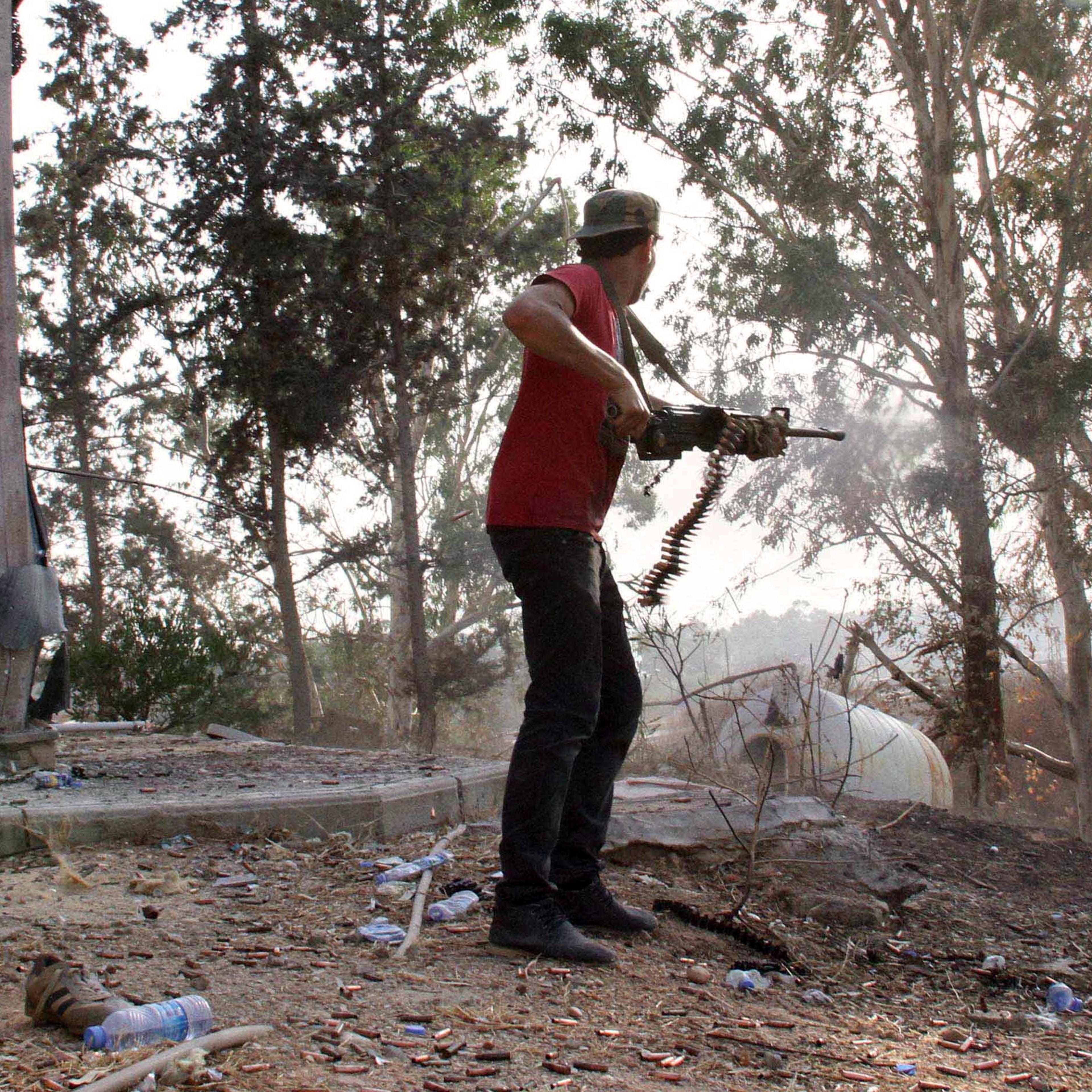 A man fires a weapon during fightings between rival militias around Tripoli international airport, on August 17, 2014.