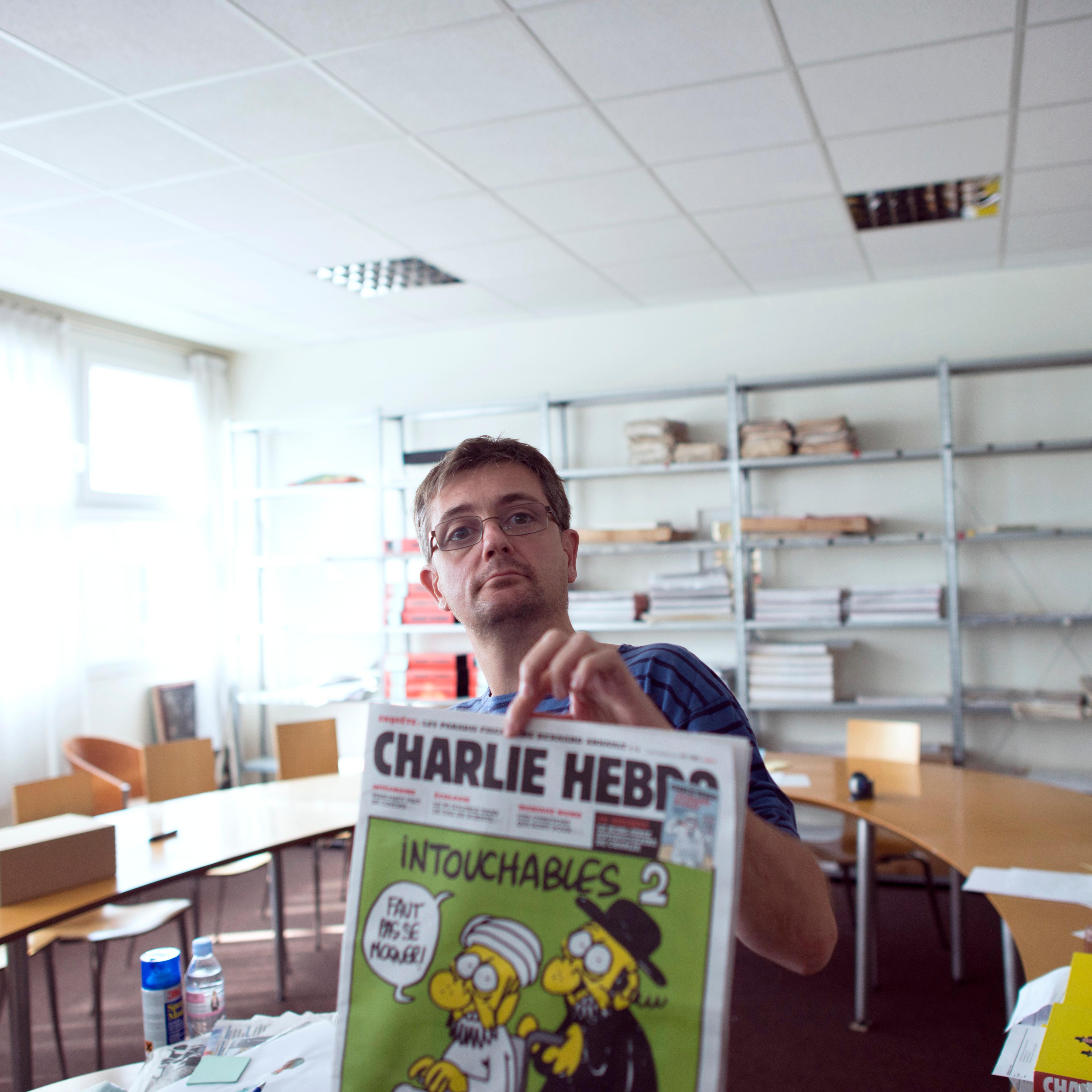 French satirical weekly Charlie Hebdo's publisher and cartoonist presents to journalists the last issue which features on the front cover a satirical drawing titled "Intouchables 2" in Paris on Sep. 19, 2012.