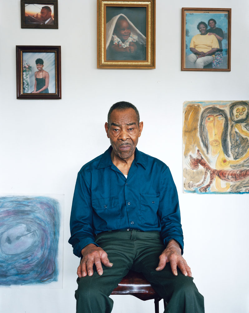 Thornton Dial at his home in Bessemer, Alabama. Surrounded by family photos and his drawings. 
