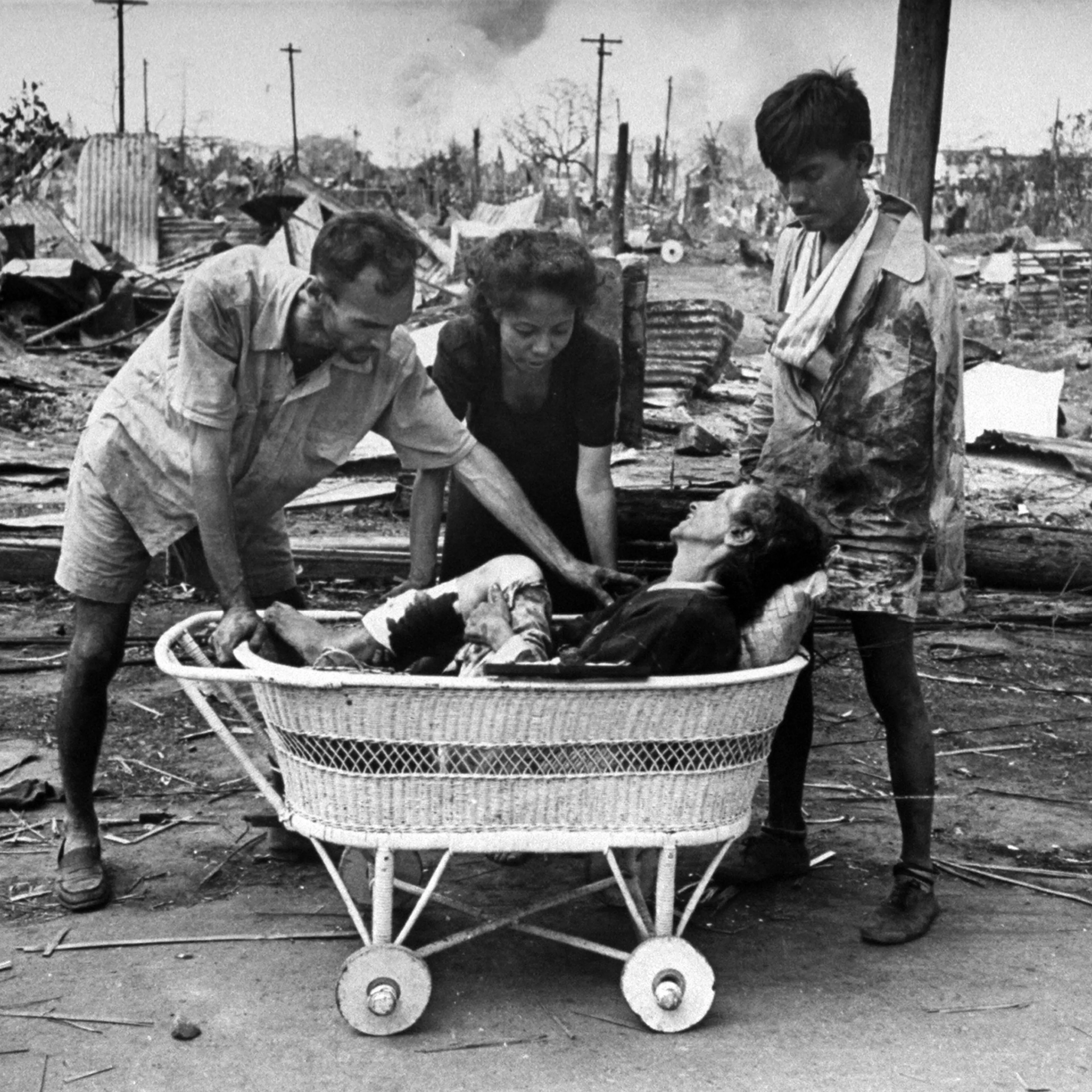 Friends using a baby carriage to transport a wounded woman to an aid station during the fight to reclaim the city from occupying Japanese troops. This image is an outtake from the March 5, 1945 photo essay: Santo Tomas is Delivered.