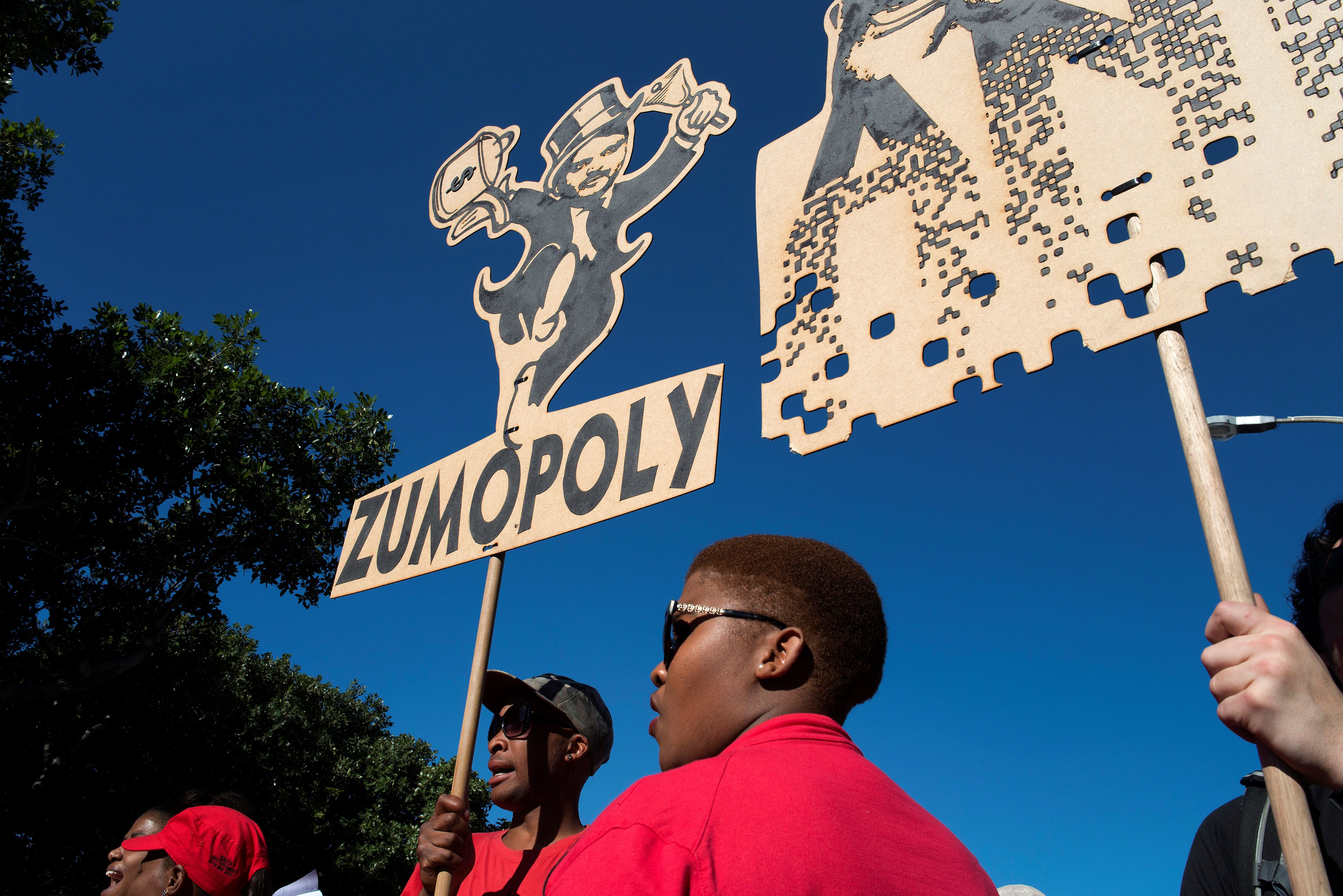 People carry a placard with a parody of one of the Gupta brothers during a demonstration march organised by a broad-based coalition called #UniteBehind, to place pressure on MPs to vote for the removal of South African President Jacob Zuma (not visible) 