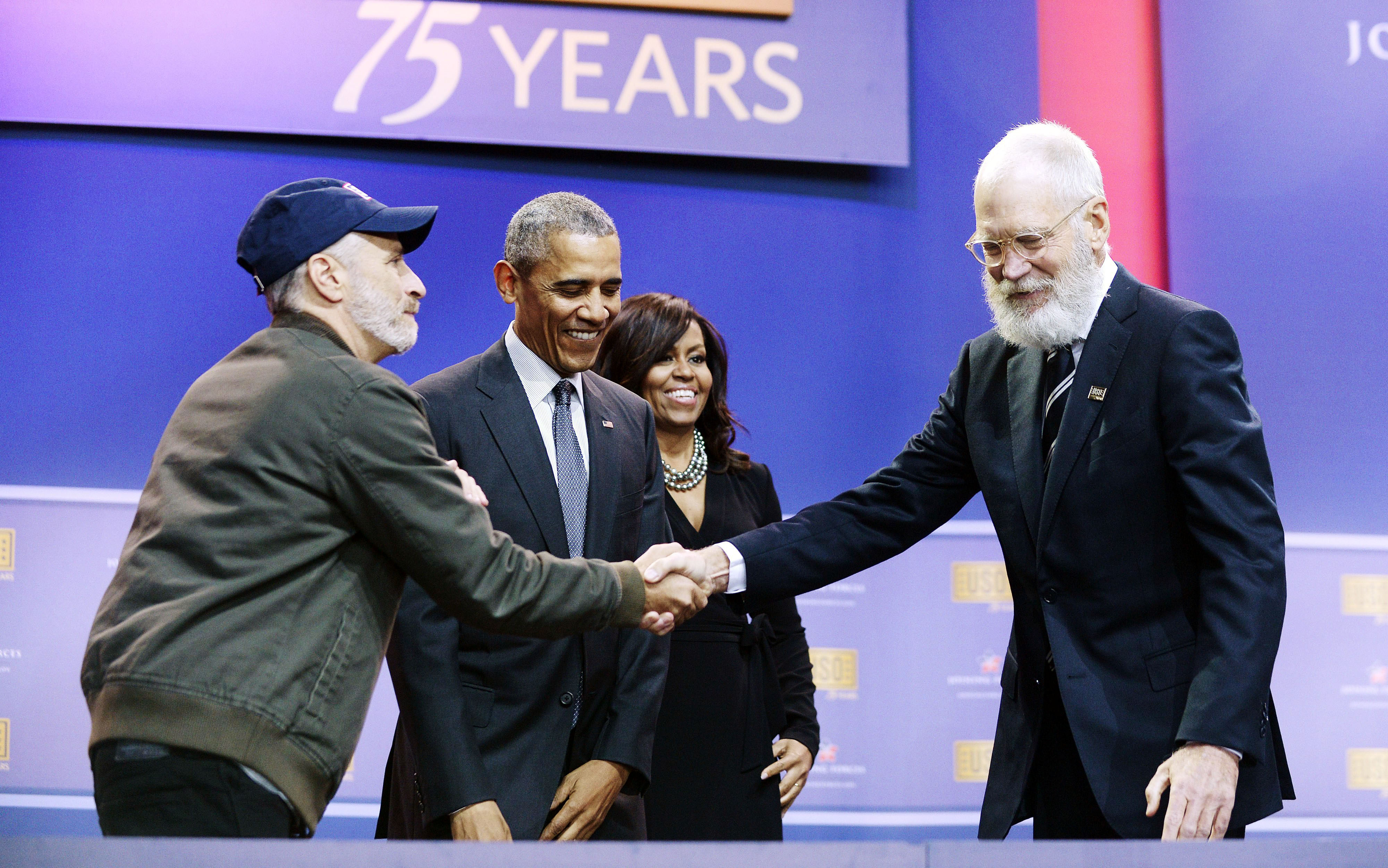 Comedian Jon Stewart shakes hands with comedian David Letterman as President Barack Obama and First Lady Michelle Obama watch at the 75th anniversary of the USO at Joint Base Andrews in Maryland on May 5, 2016.